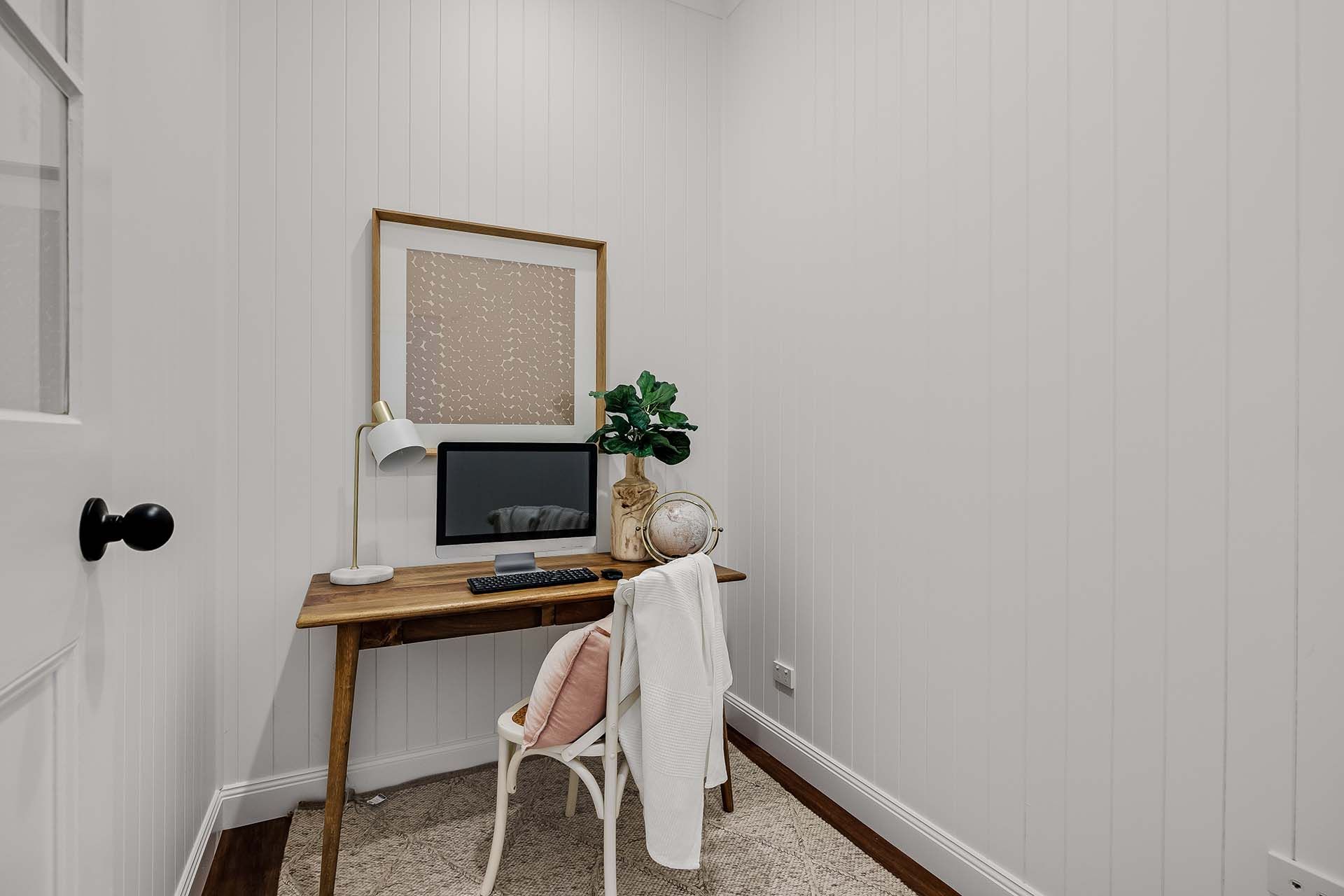 there is a desk with a computer on it in the corner of the room .
