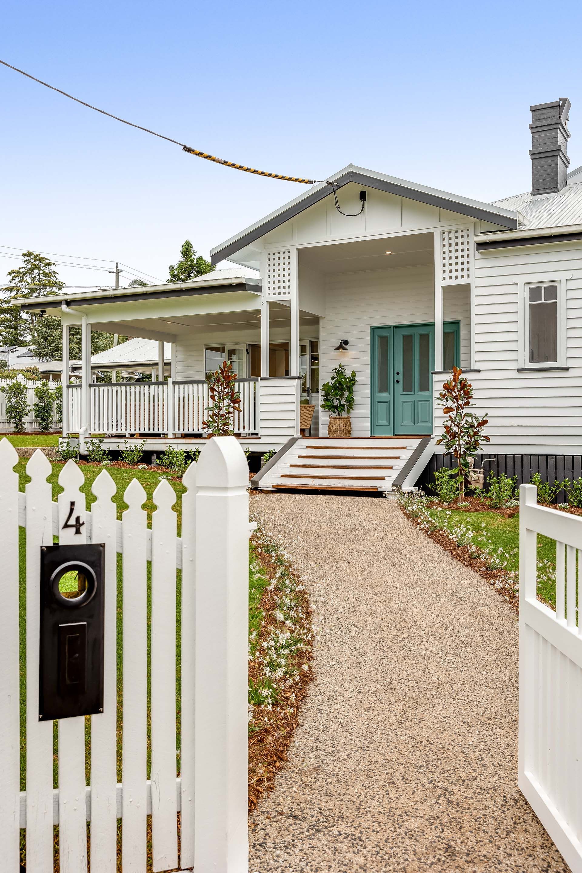 a white house with a white picket fence and a gravel path leading to it .