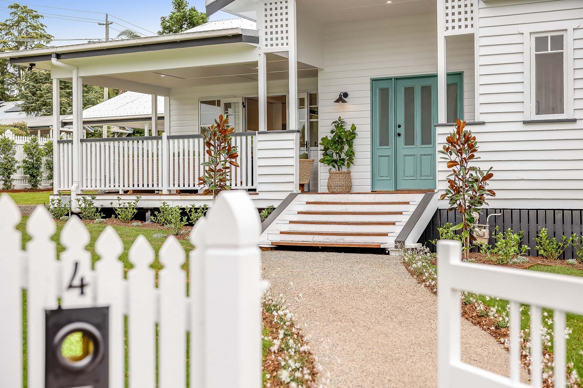 a white picket fence surrounds a white house with a green door .