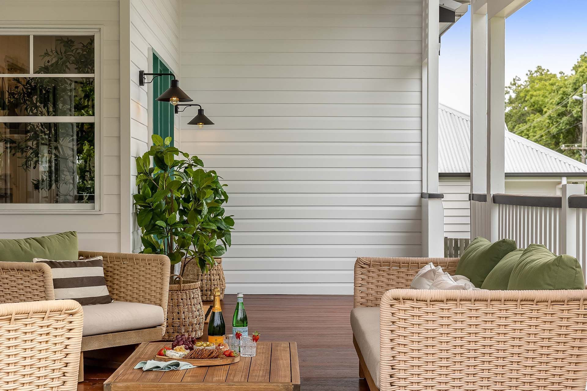 a patio with wicker furniture and a table with a bottle of champagne on it .