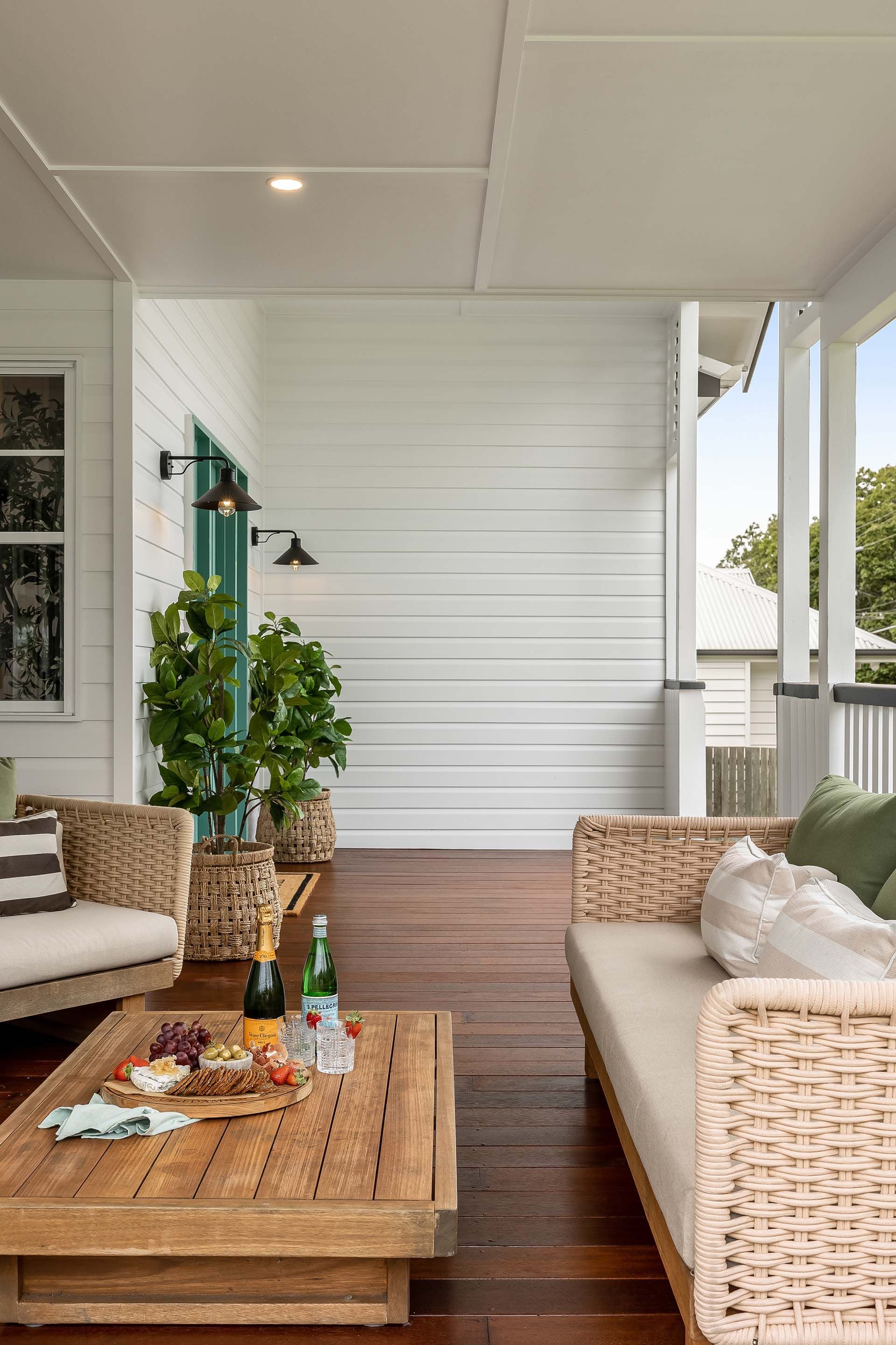 there is a table with a bottle of wine on it on the porch .
