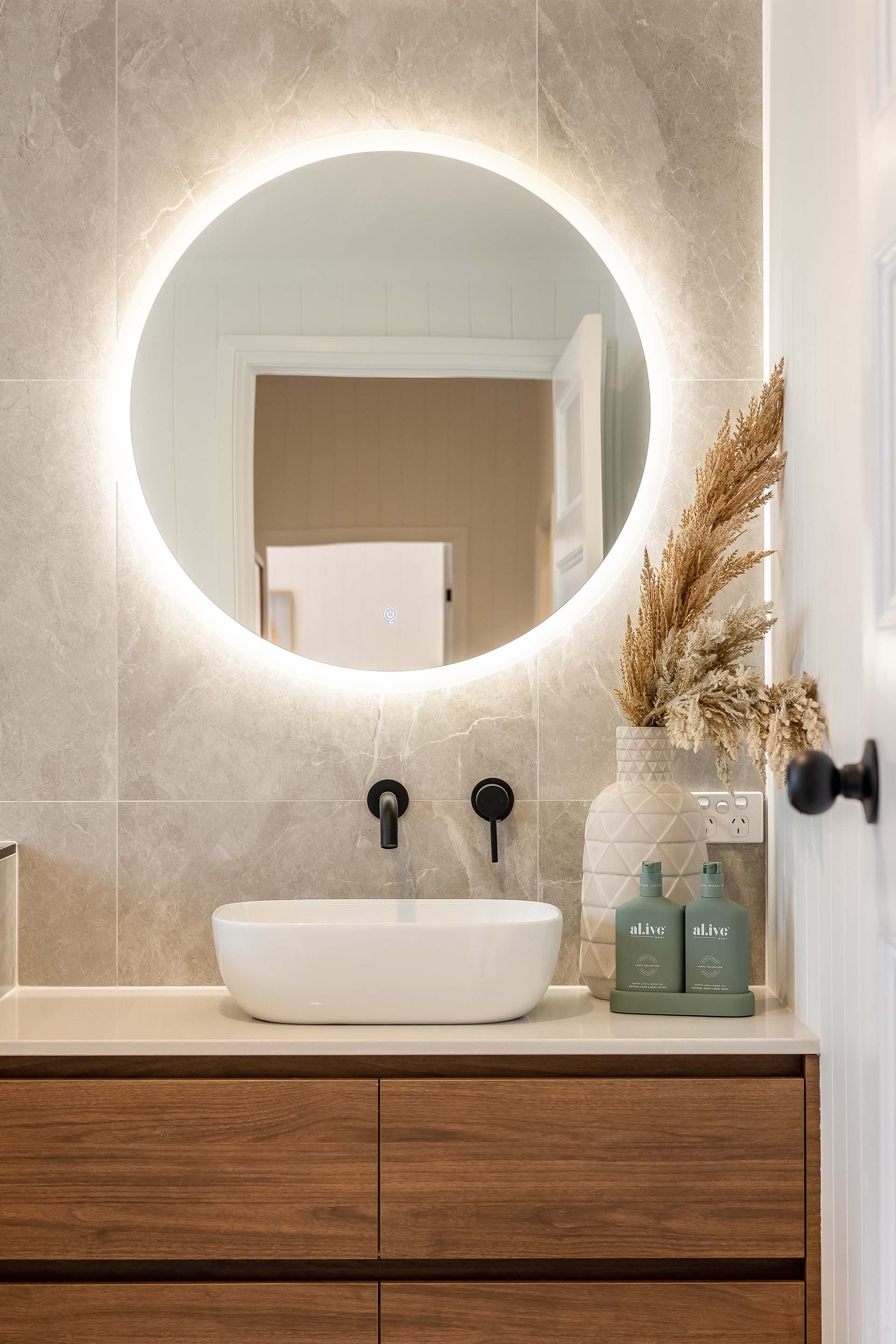 a bathroom with a sink and a round mirror .
