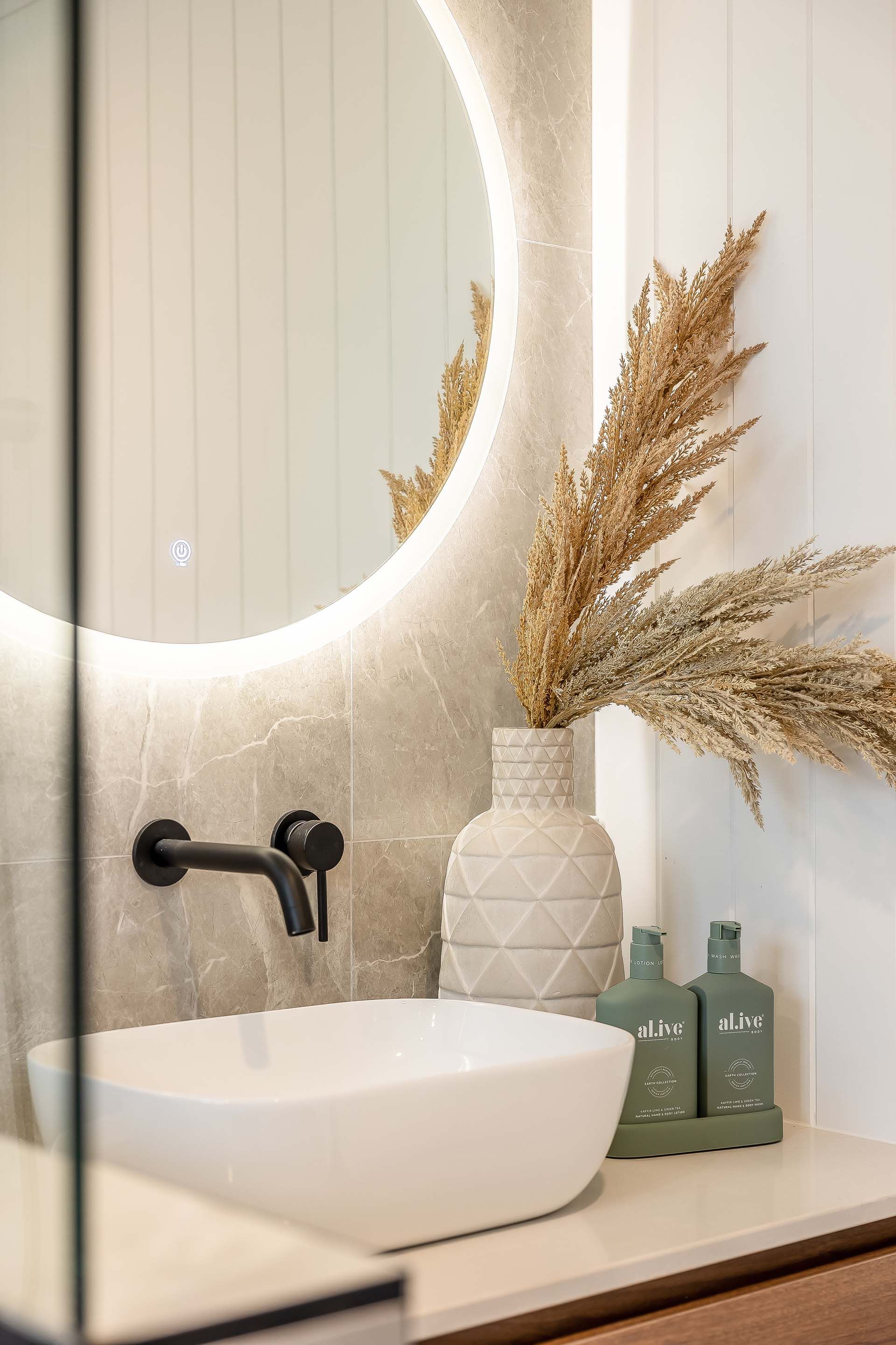a bathroom with a sink , mirror and vases .