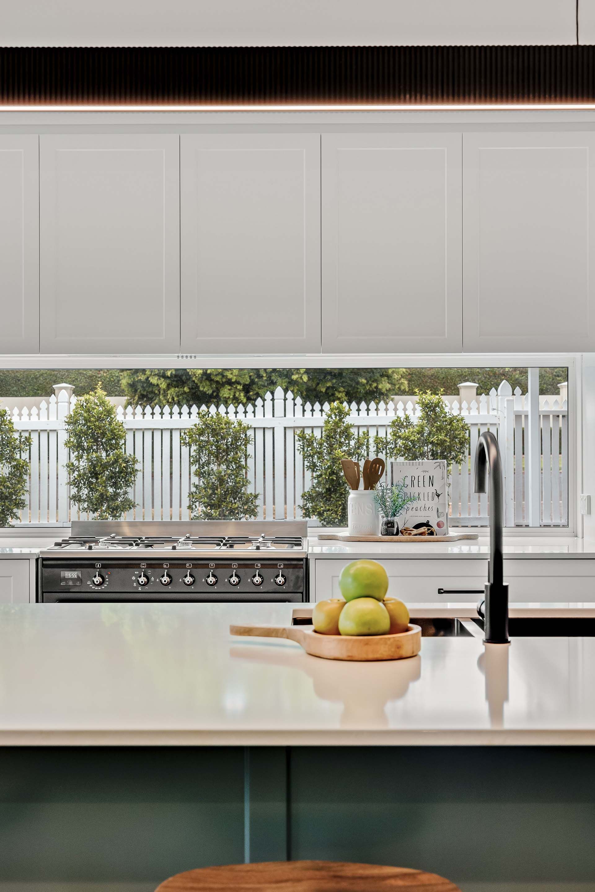 a kitchen with white cabinets , a stove , a sink , and a window .