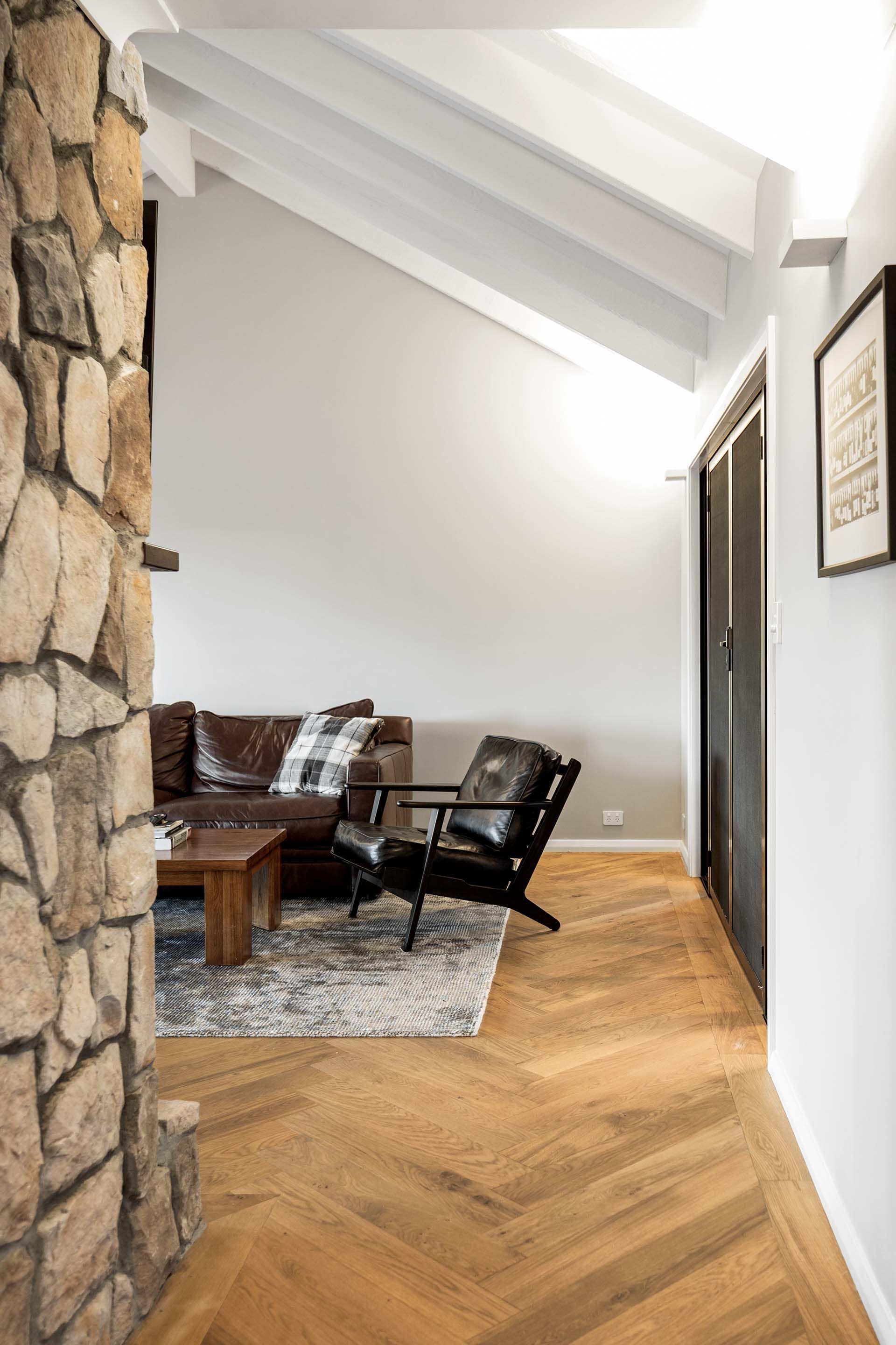 a living room with a couch , chairs , and a stone fireplace .