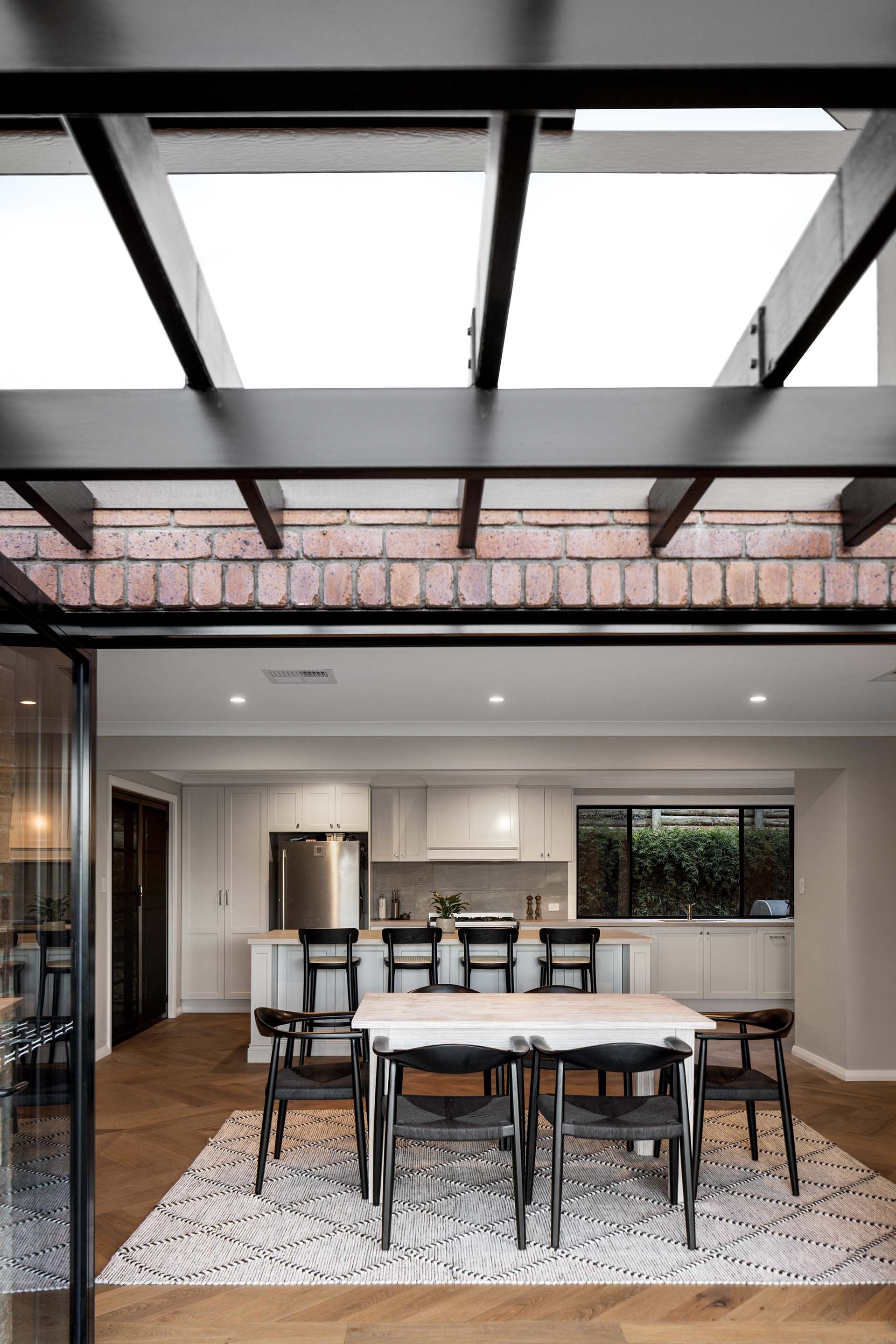 a dining room with a table and chairs under a pergola .