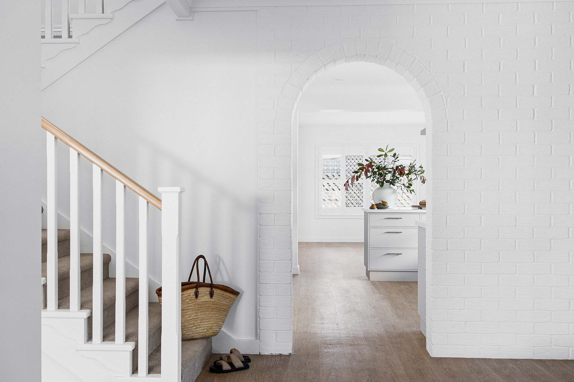 a hallway with stairs leading up to a kitchen and a basket on the floor .