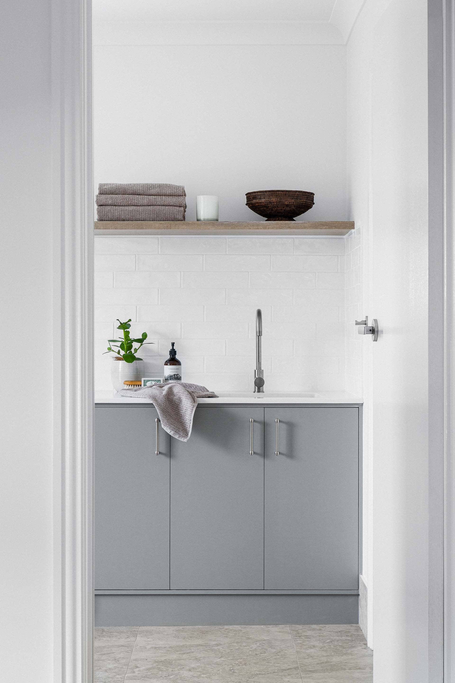 a laundry room with gray cabinets and a sink .