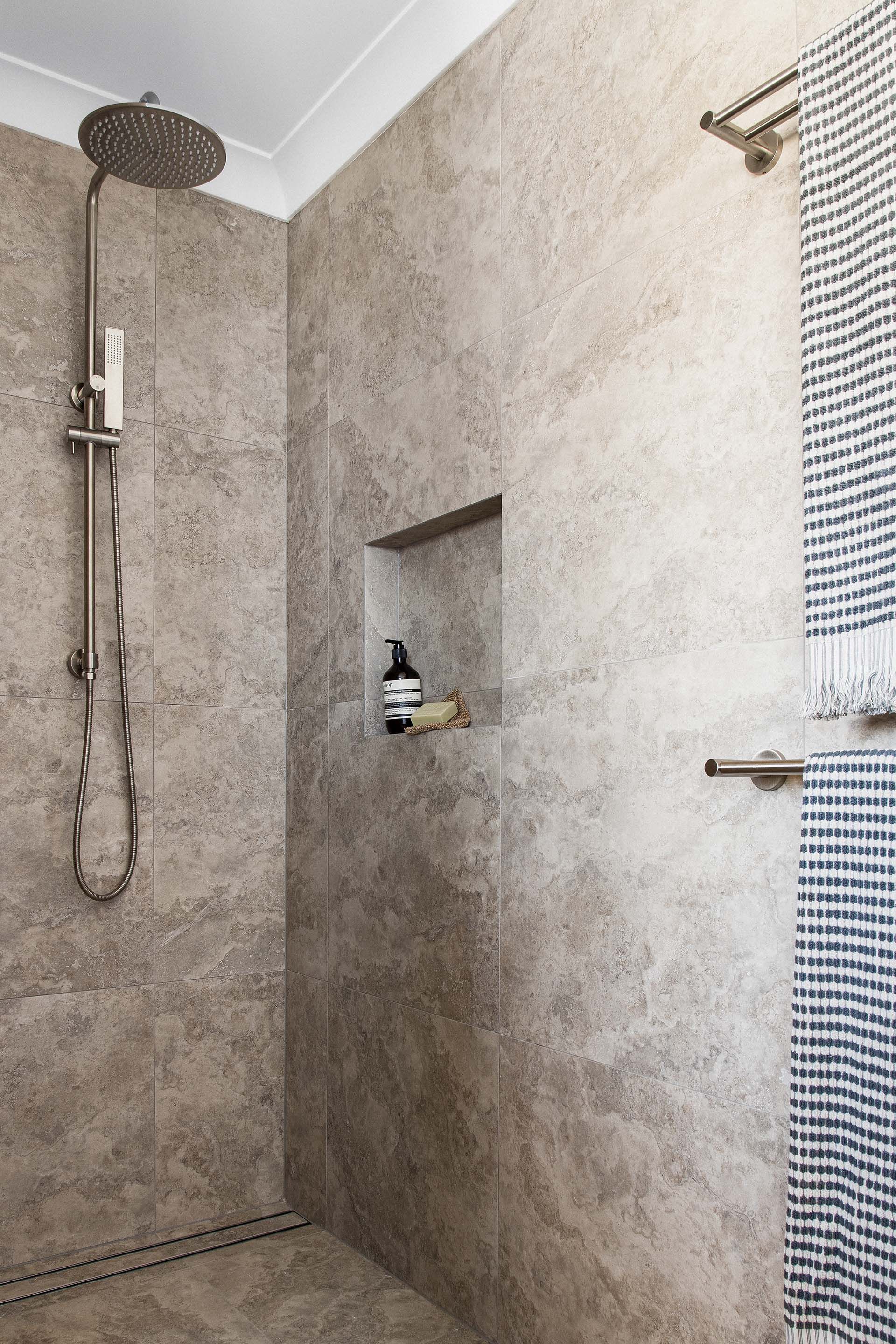 a bathroom with a walk in shower and a shelf .