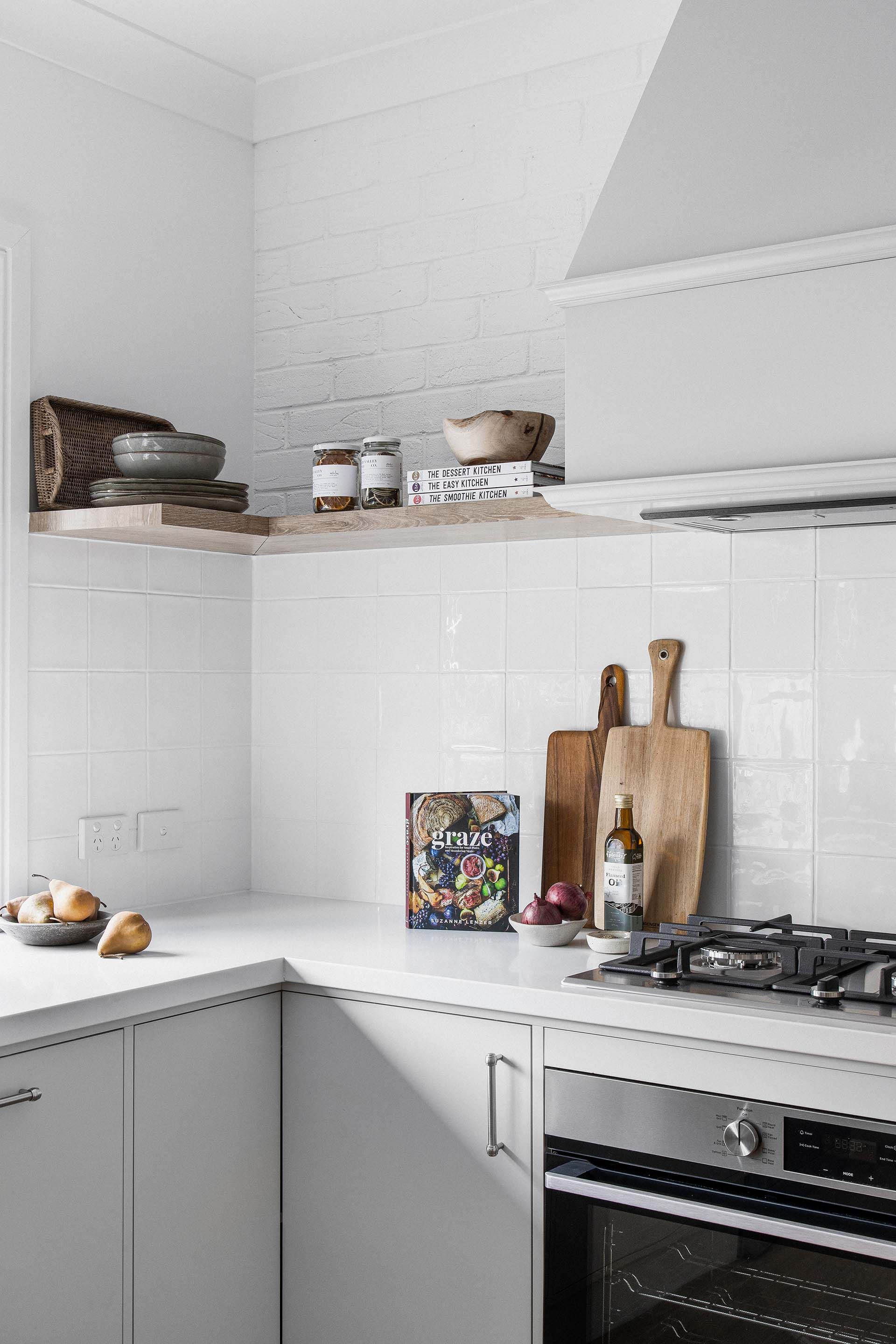 a kitchen with white cabinets , a stove , and a cutting board on the counter .