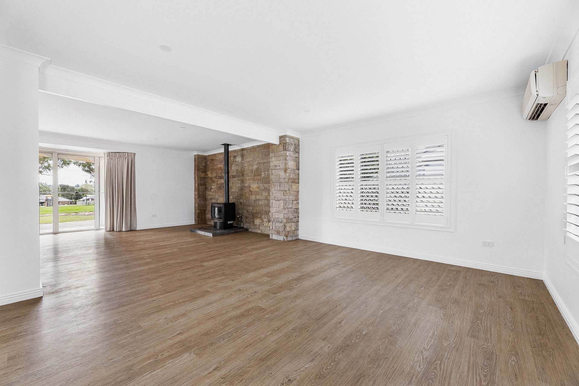 an empty living room with hardwood floors and a fireplace .