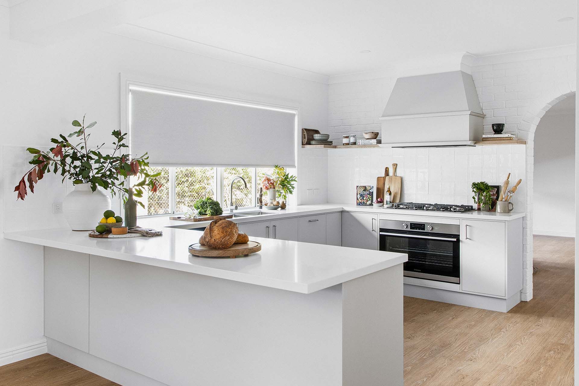a kitchen with white cabinets , a large island , a stove , and a window .