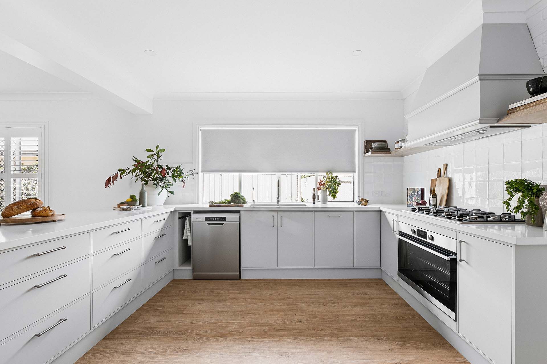a kitchen with white cabinets , stainless steel appliances , and a wooden floor .
