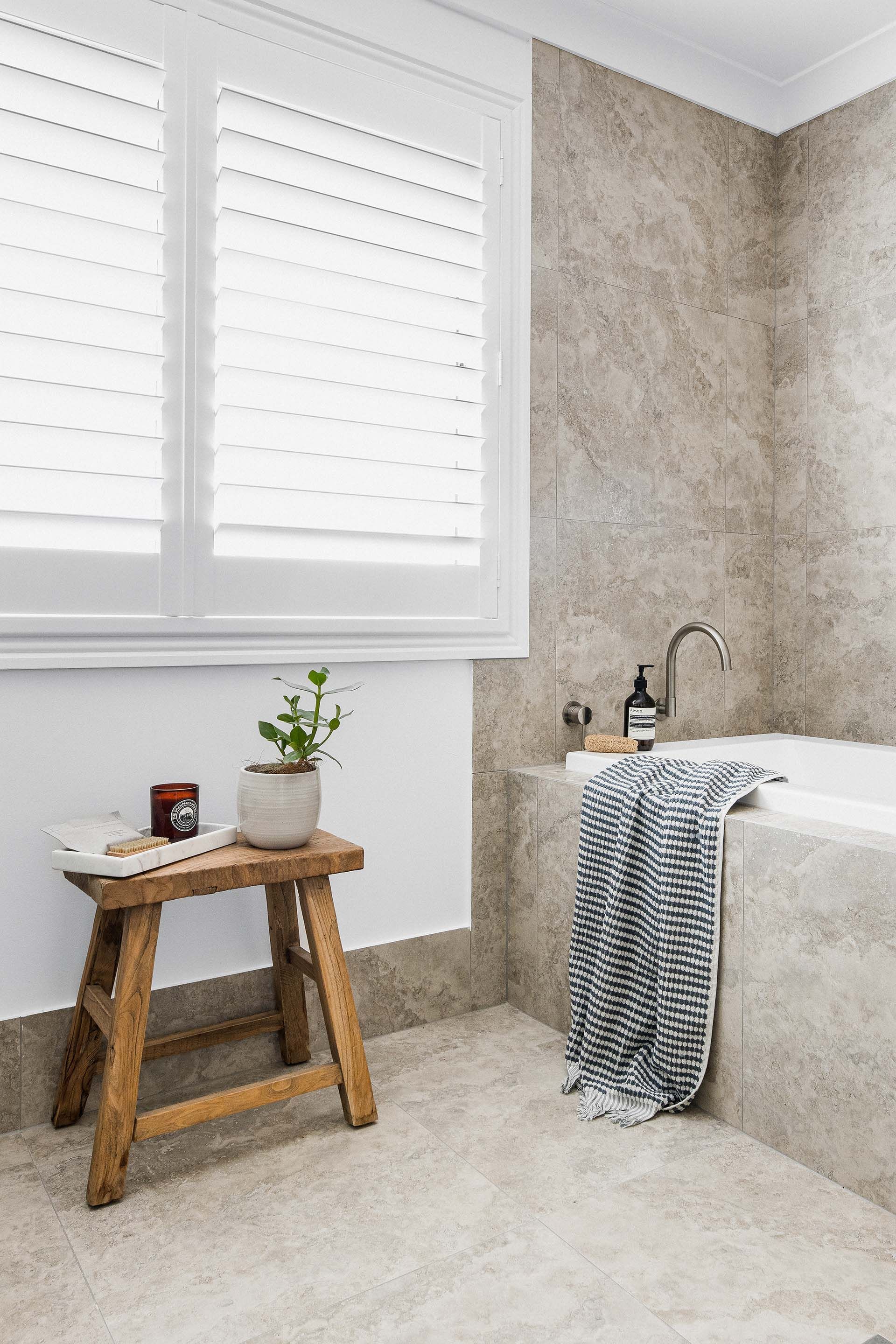a bathroom with a wooden stool next to a bathtub .
