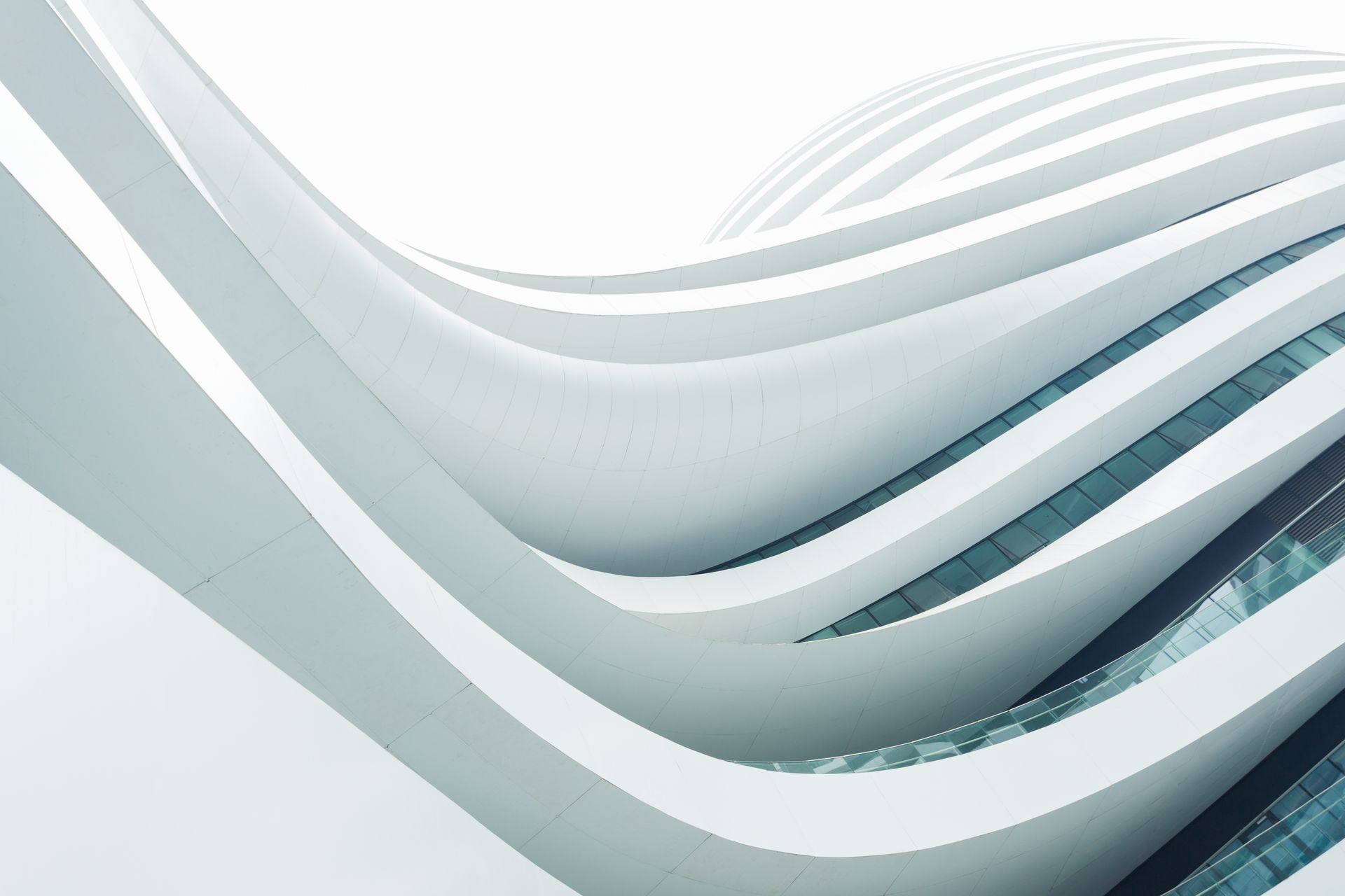 White, modern building with curved, flowing lines; sky visible in background.