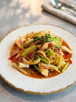 Plated vegetable stir-fry in a savory sauce on a white dish, served on a tabletop.