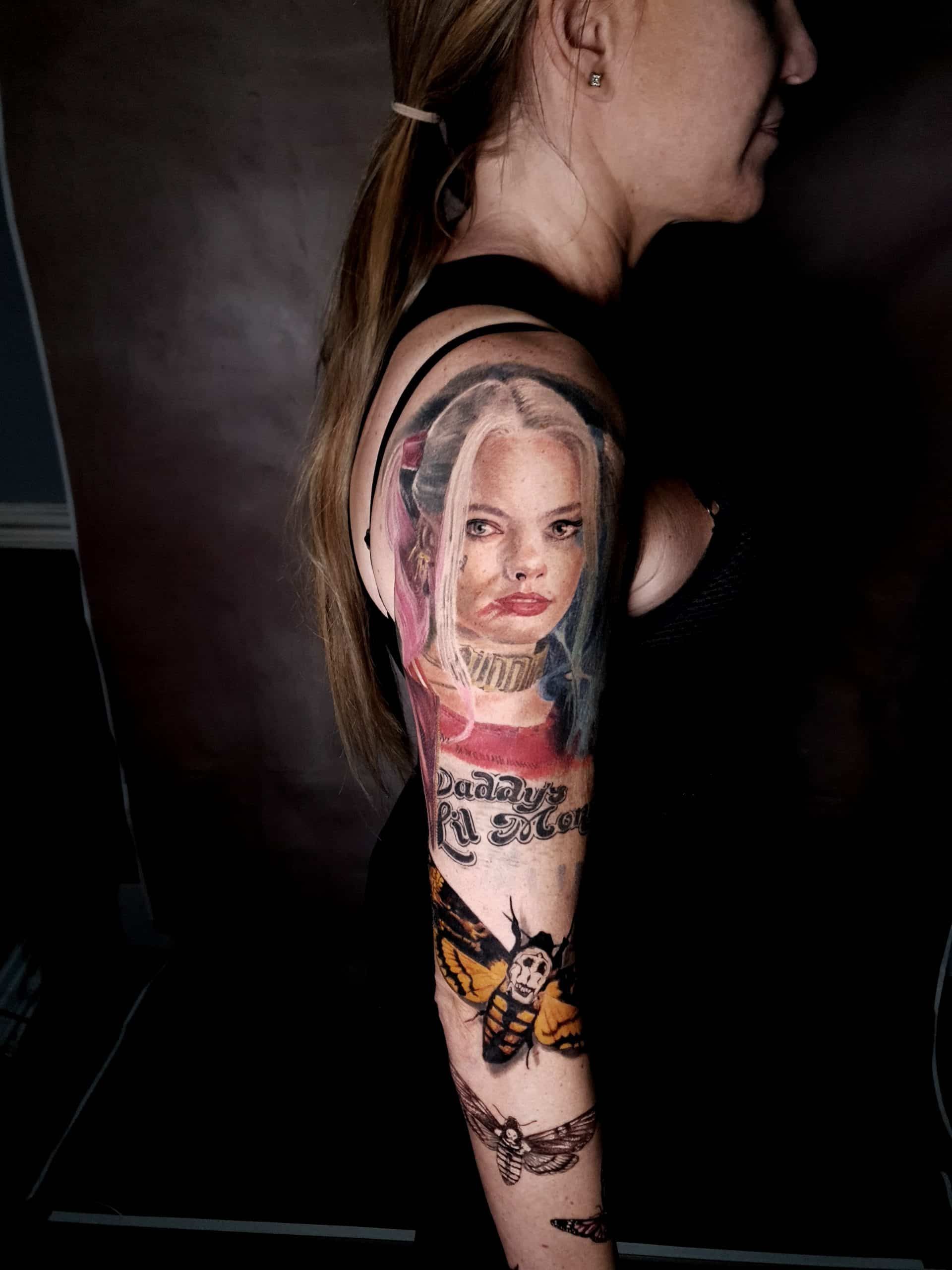 Side view of a tattooed arm showing a large portrait tattoo with pink and black details