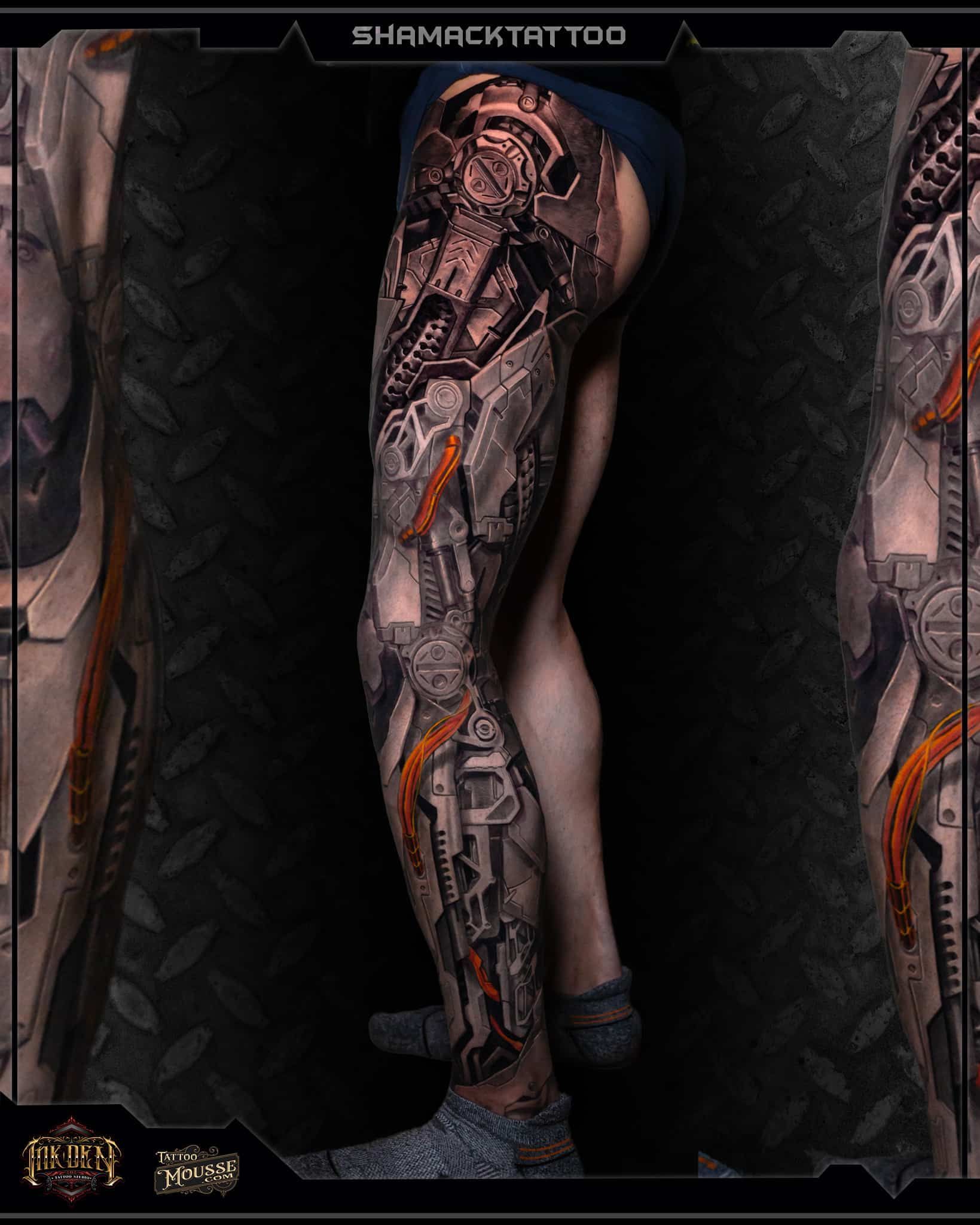 Close-up of a tattooed leg with dark, futuristic patterns in a dim, metallic setting