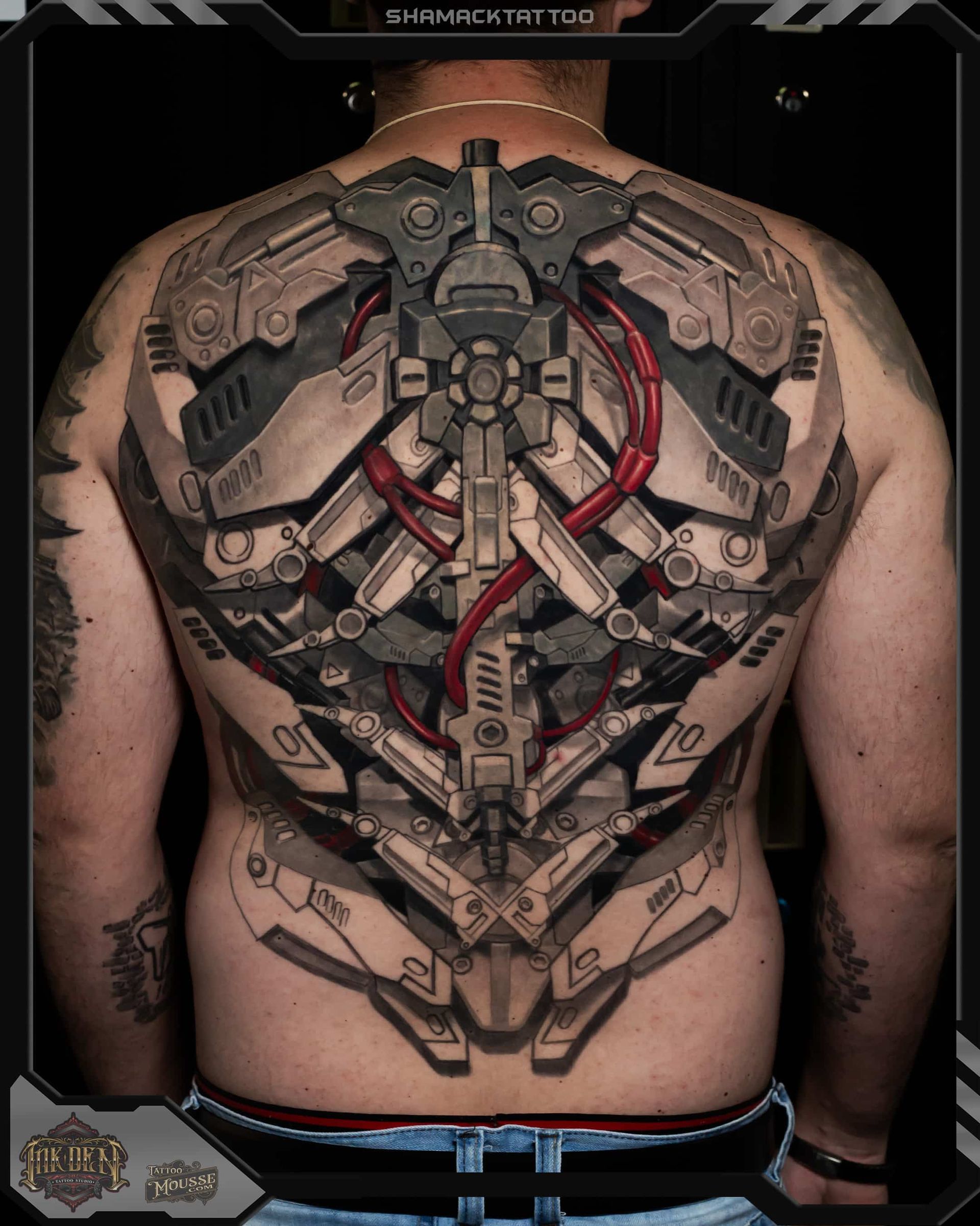 A back tattoo of a futuristic mechanical exoskeleton in gray, red, and black across the shoulders and spine