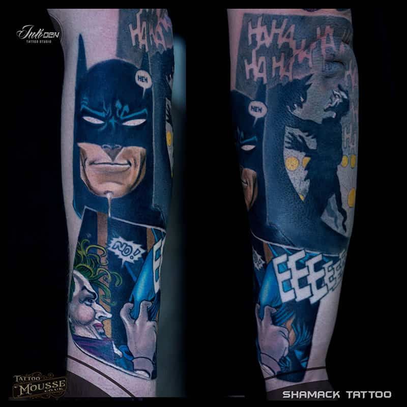 Batman tattoo on a leg in dark blue, showing comic-style panels with Joker and “HA HA” text