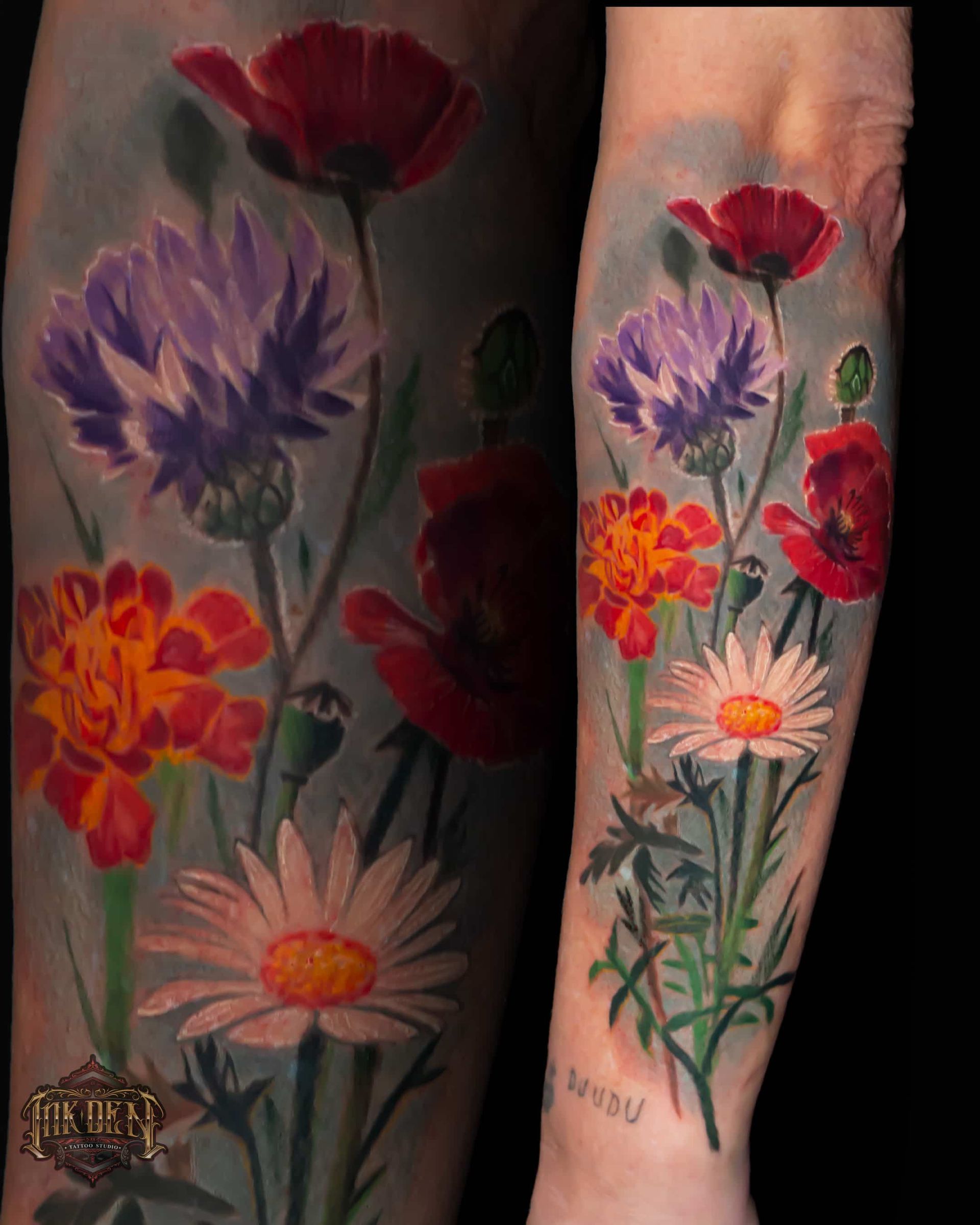 Colorful floral tattoo on a forearm, with red, purple, orange, and white flowers and green stems.