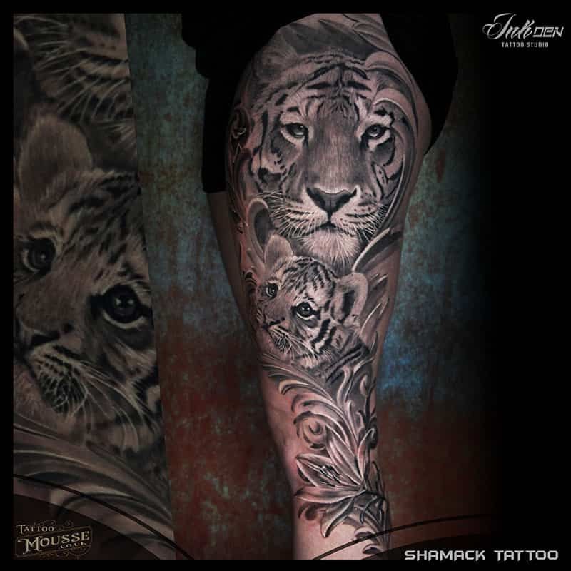 Black and gray tiger tattoo on a lower leg, with a tiger face and floral shading