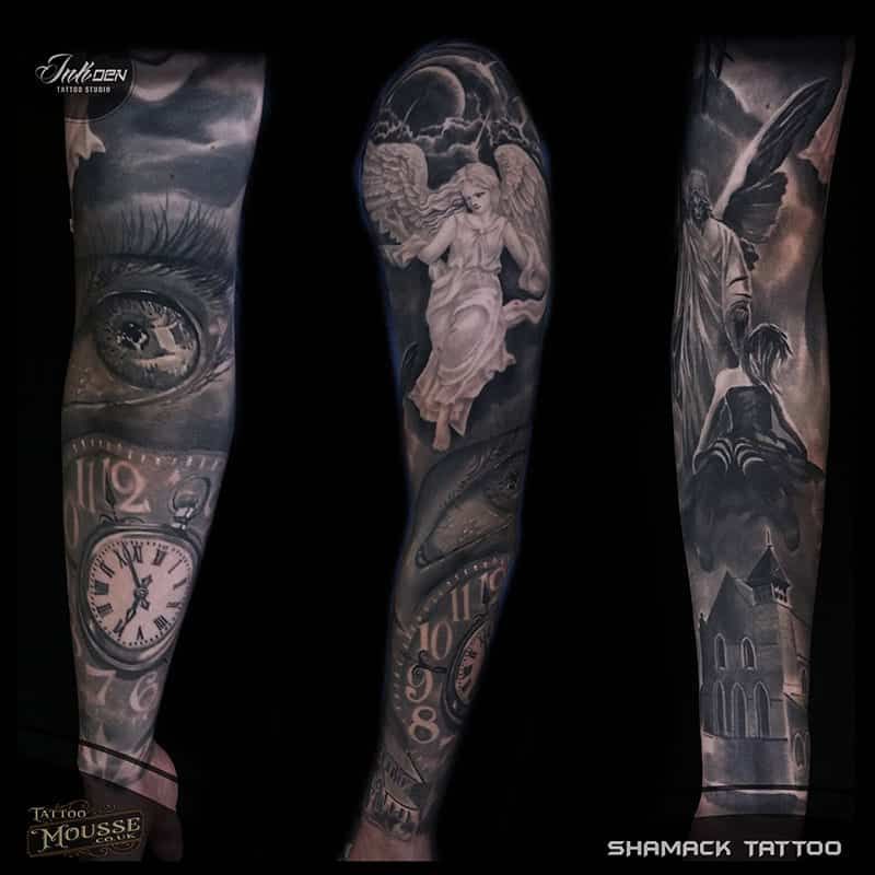 Three black-and-gray tattooed forearms with clock, angel, and bird designs on a black background