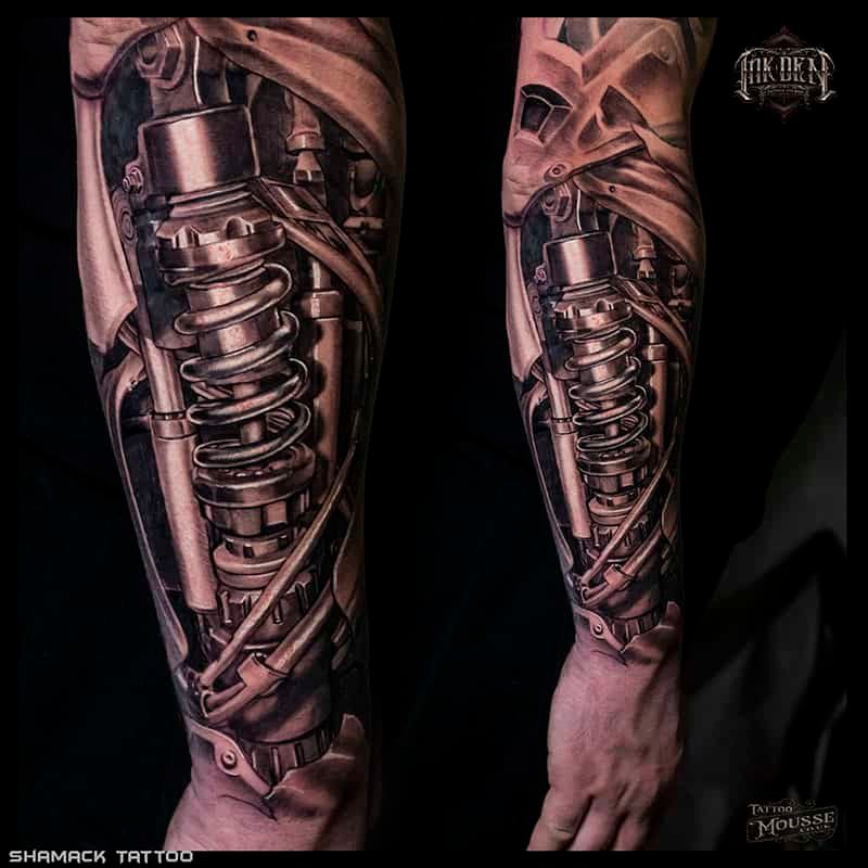 Close-up of two tattooed forearms with mechanical spring-and-gear designs in black and gray ink