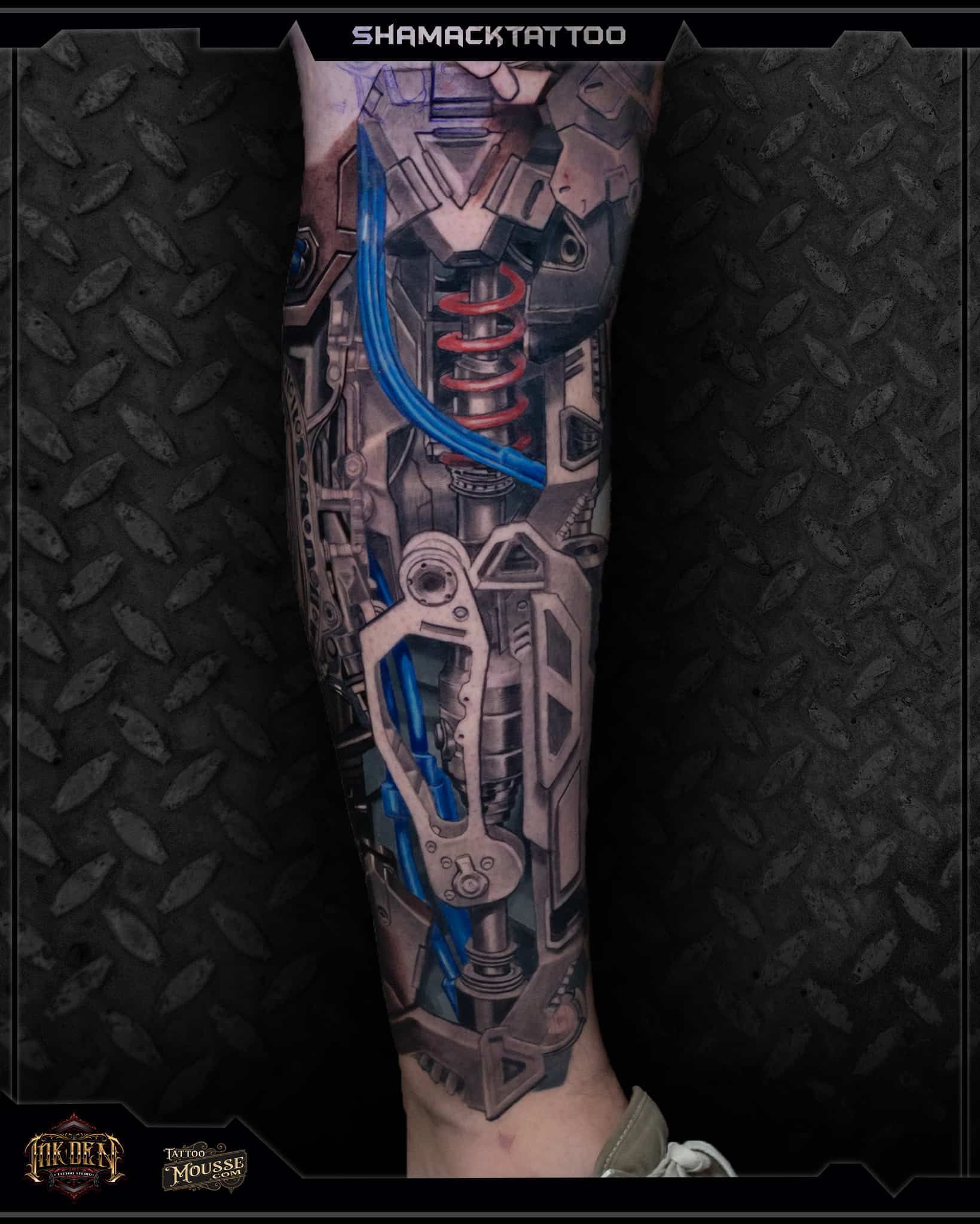 Tattooed forearm with a blue and red mechanical skull design on a dark textured background