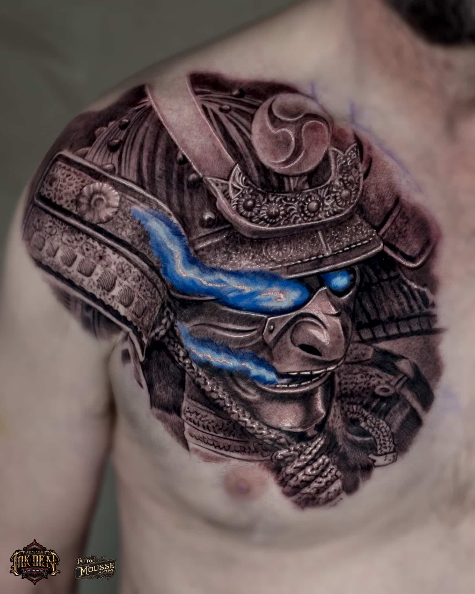 Samurai helmet chest tattoo with blue lightning-like streaks and intricate black-and-gray shading