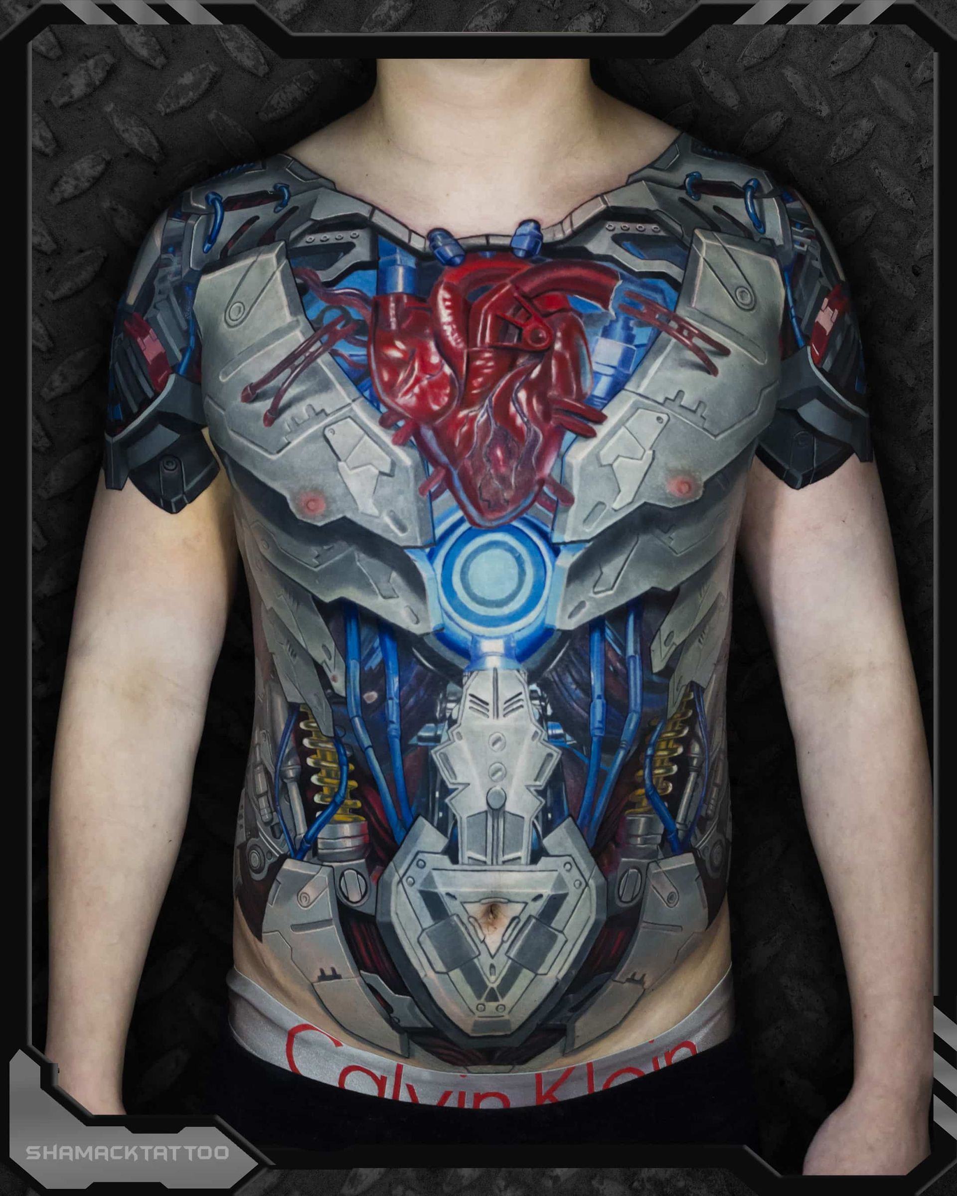 Person wearing a realistic Iron Man torso body paint design on a gray shirtless upper body