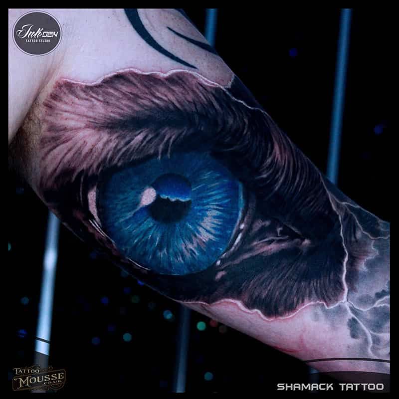 Blue eye tattoo on skin with realistic lashes and smoky black-gray shading