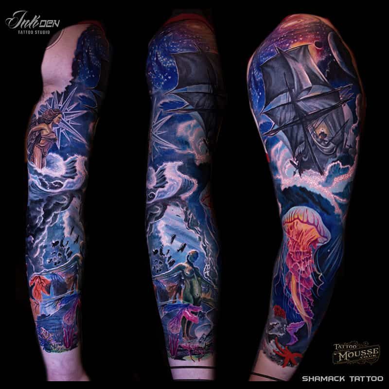 Arm tattoo sleeve design with blue, purple, and pink fantasy ocean and ship scenes on a black background