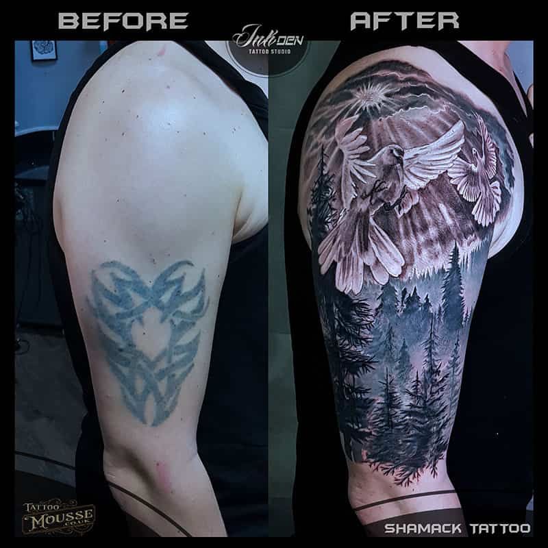 Before-and-after tattoo cover-up on a shoulder: blue tribal design replaced with a black mountain-and-forest scene.