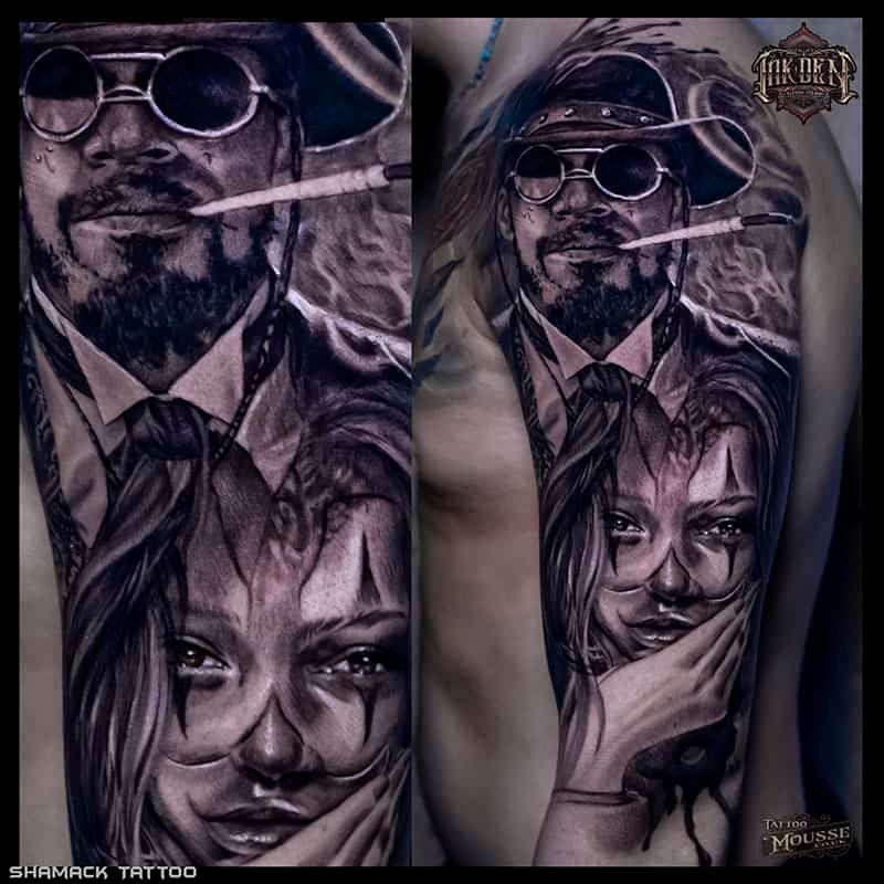 Tattoo design of a man in a hat and sunglasses above a woman’s face in purple and gray tones