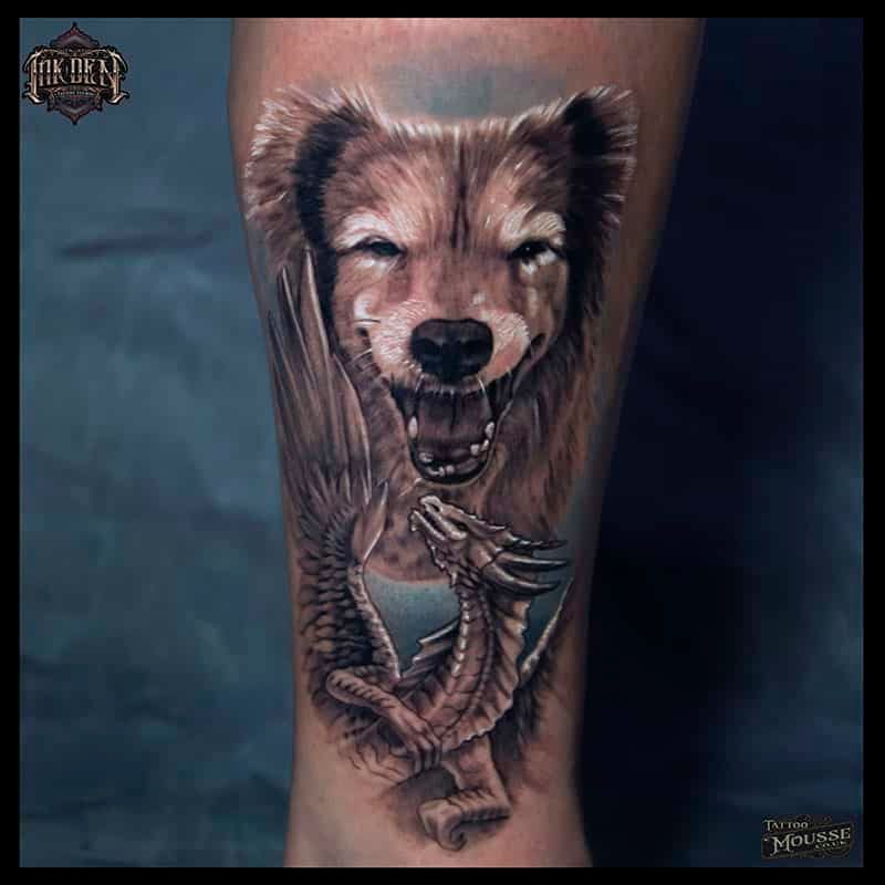 Tattoo of a roaring bear with a dragon wrapped around the lower leg