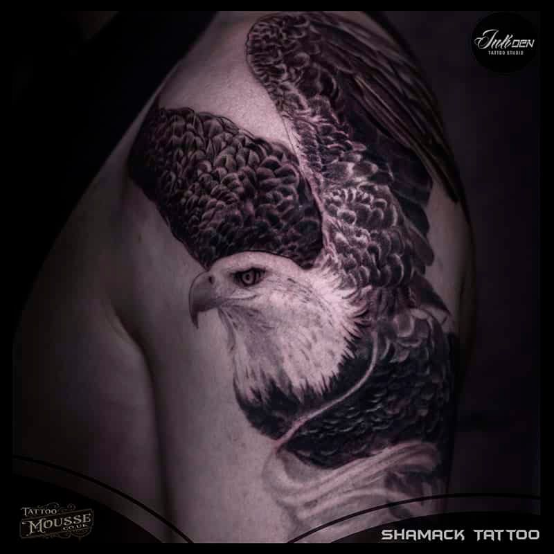 Black and gray tattoo of a bald eagle with wings spread on a person’s shoulder