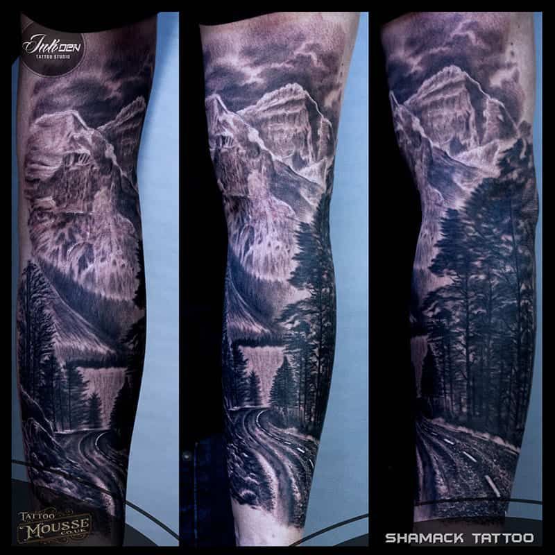 Three vertical black-and-gray mountain and forest tattoo designs on a blue background