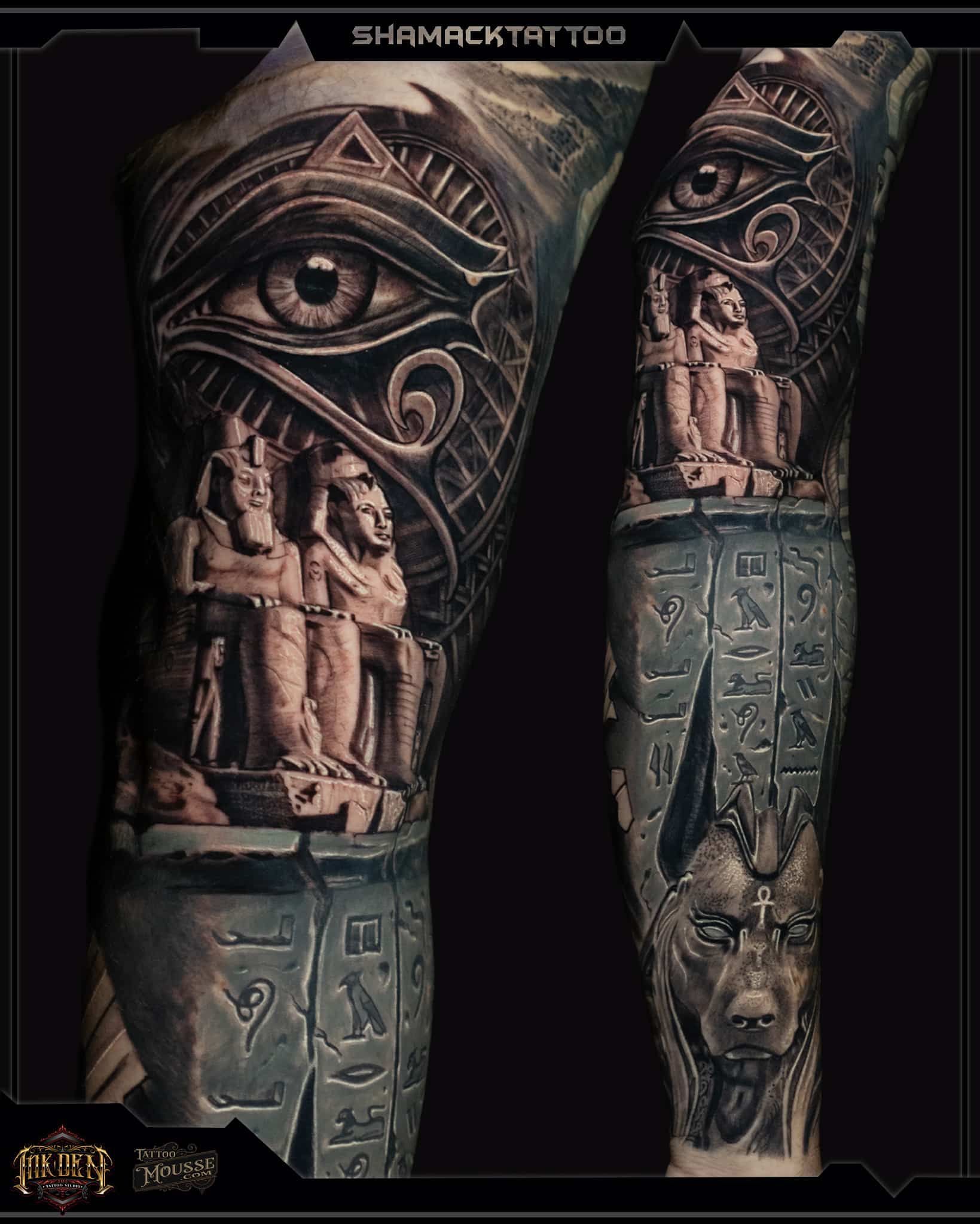 Two carved forearms with an eye motif and Egyptian-style figures, in dark bronze and stone tones