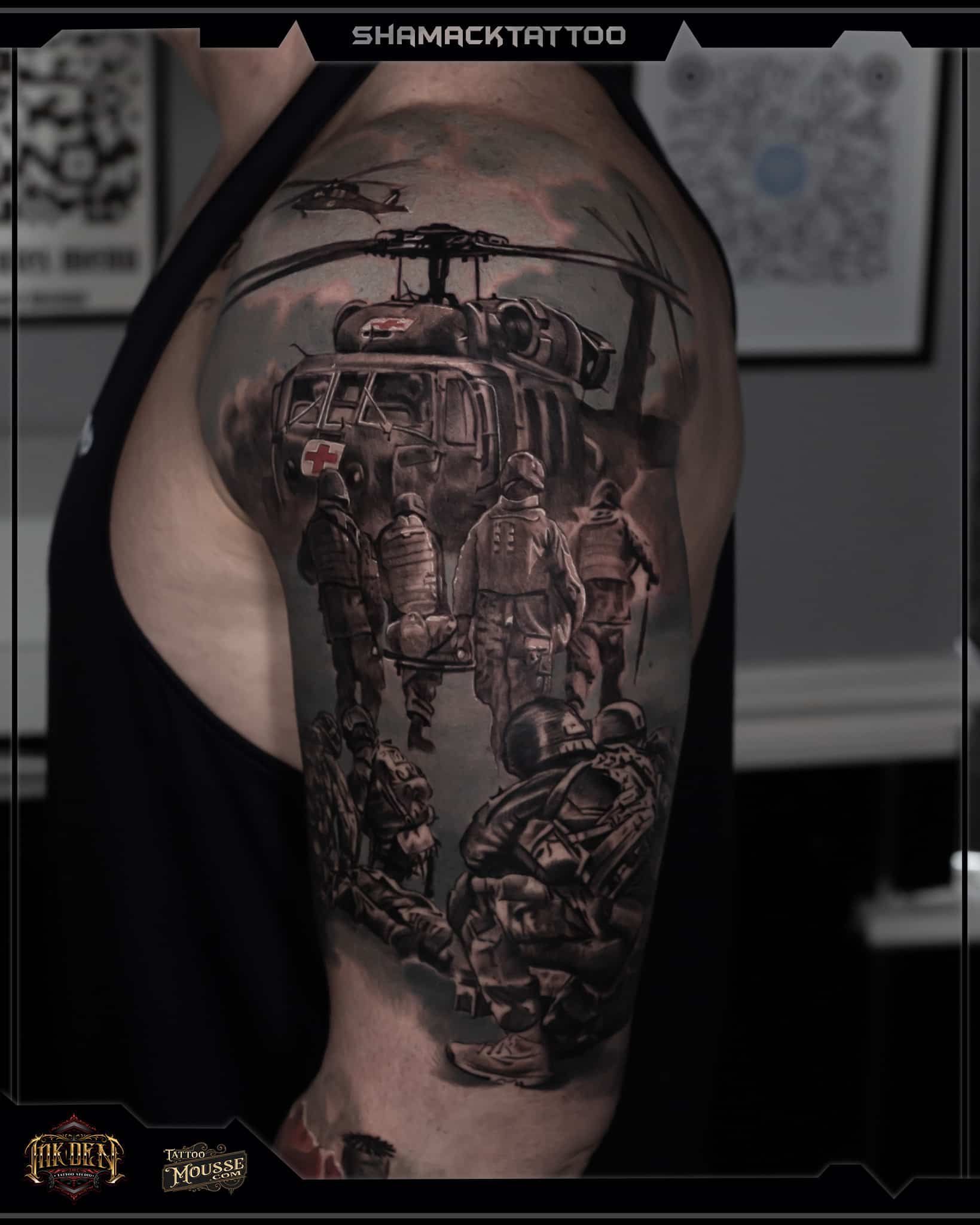Close-up of a large black-and-brown helicopter tattoo on a person’s upper arm and shoulder.
