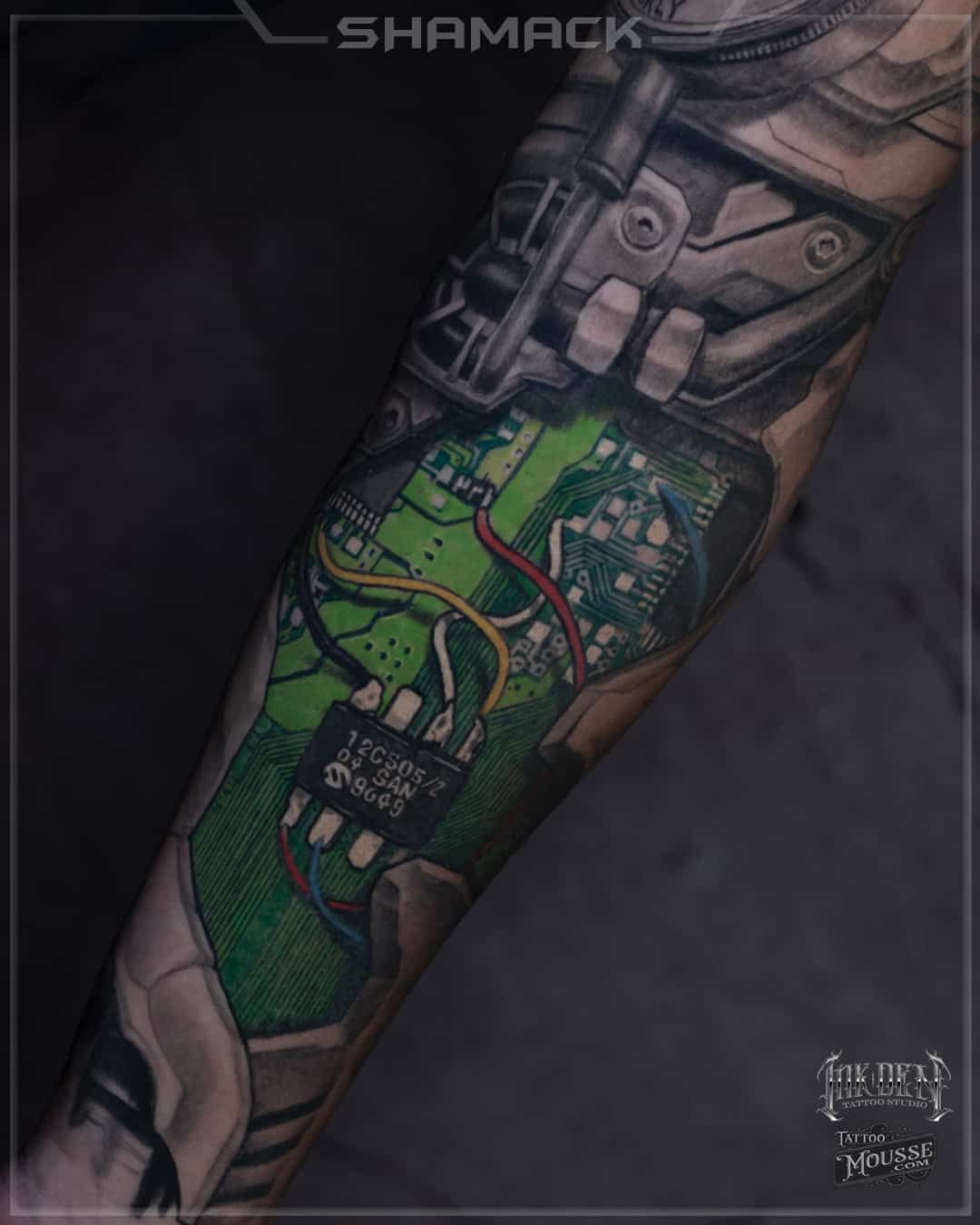 Tattoo sleeve with a green map-like landscape and grayscale machinery details on an arm