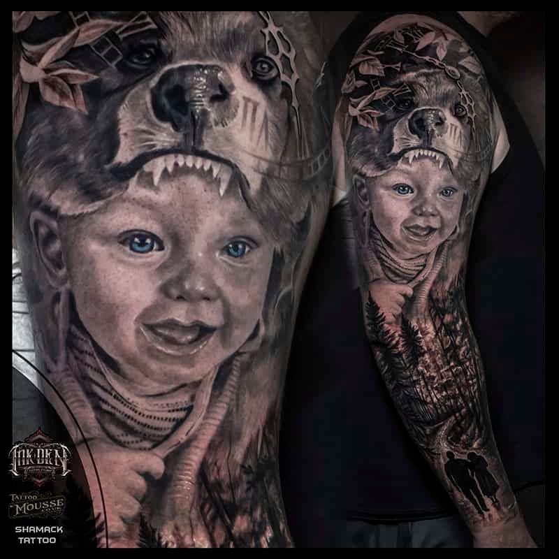 Tattoos of smiling children’s faces and a large animal face on two arms, in black and gray with color accents