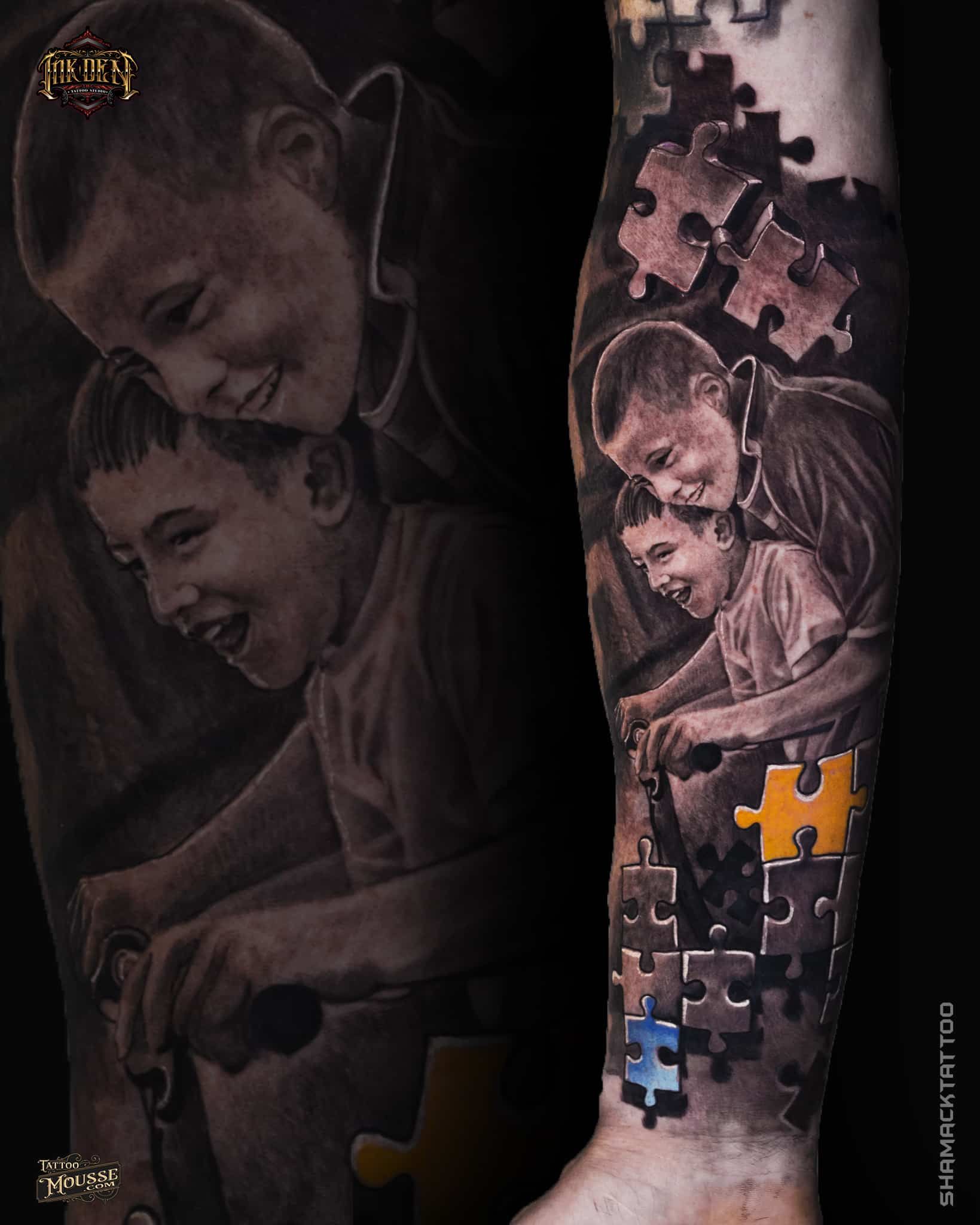 Arm tattoo of a smiling child in grayscale, with puzzle-piece accents and black background