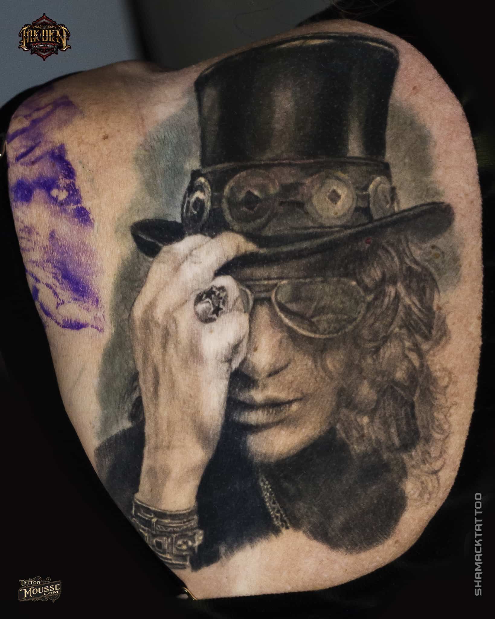 Portrait tattoo of a man in a top hat and glasses, shading one eye with a hand.