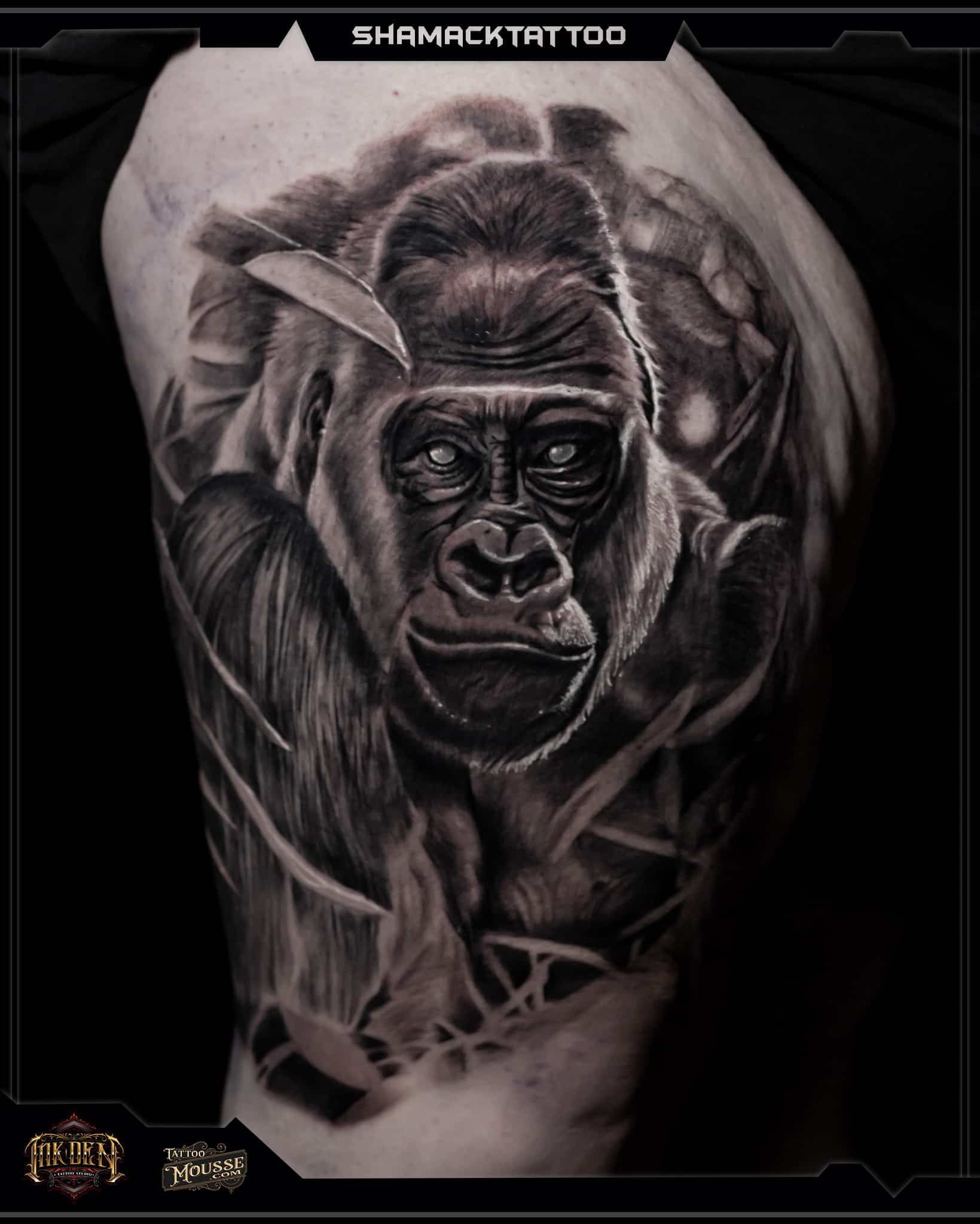 Black-and-gray tattoo of a gorilla face with a moon-like halo on a person’s upper arm
