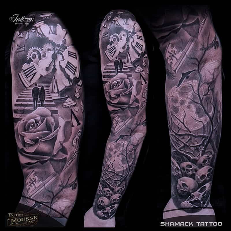 Three tattooed arms with black-and-gray floral, skull, clock, and portrait sleeve designs on a dark background