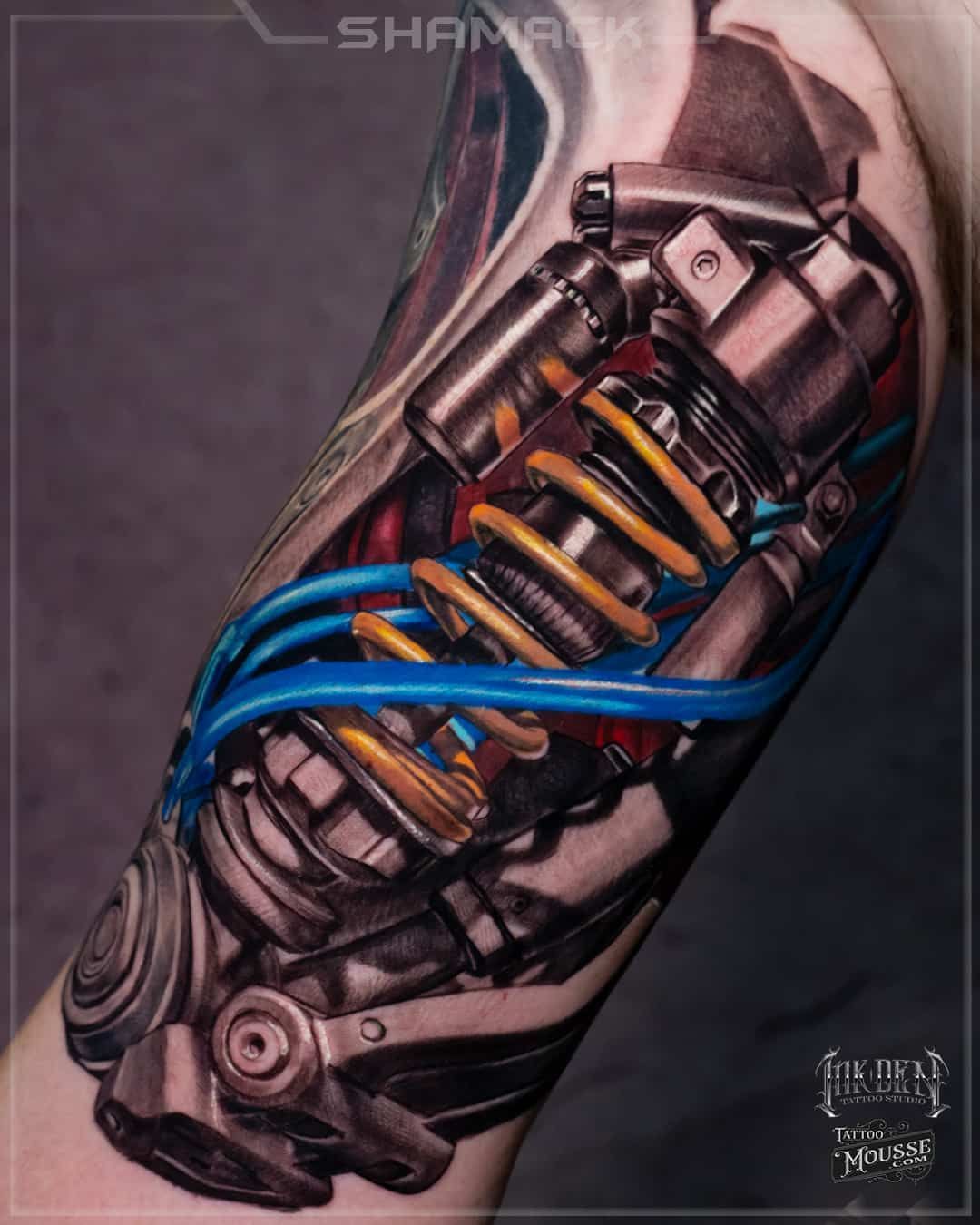 Biomechanical tattoo of a robotic arm with blue cables and orange coils on a forearm