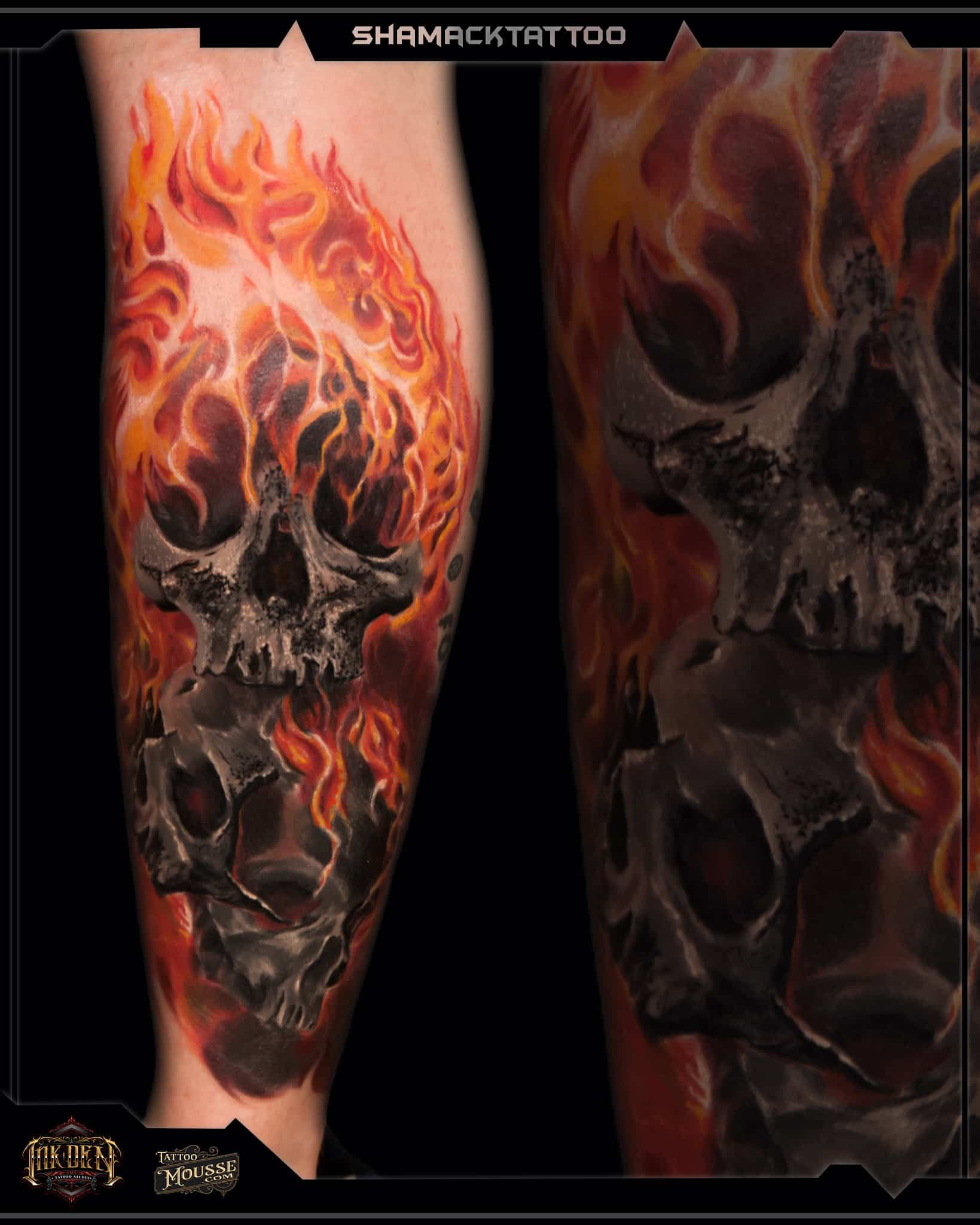 Close-up of a flaming skull tattoo on skin, with orange-red flames and dark, shadowy details.