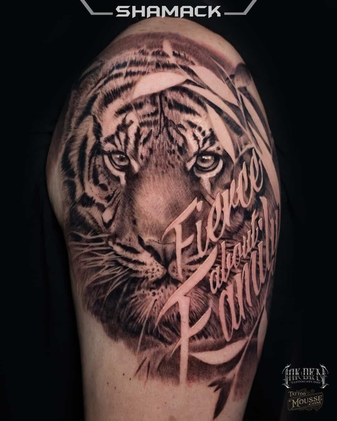 Tiger face tattoo with cursive lettering on a shaved head, shown in close-up.
