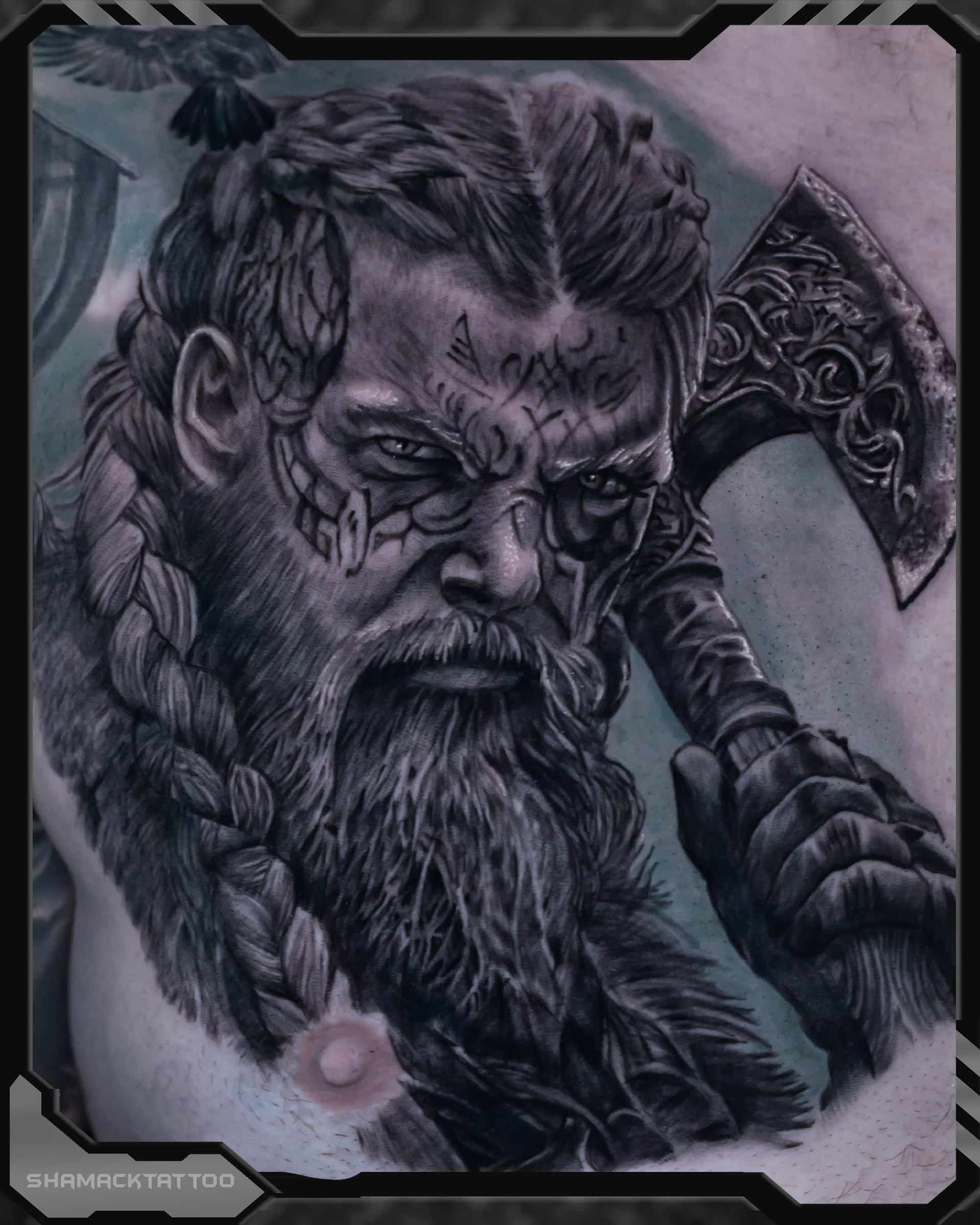 Detailed black-and-gray tattoo of a bearded warrior holding an ornate axe, with a stern expression